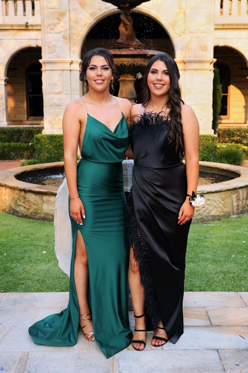 Sydney Event Photography - Two formal dresses, one emerald green and one black, elegantly posed by a garden fountain.