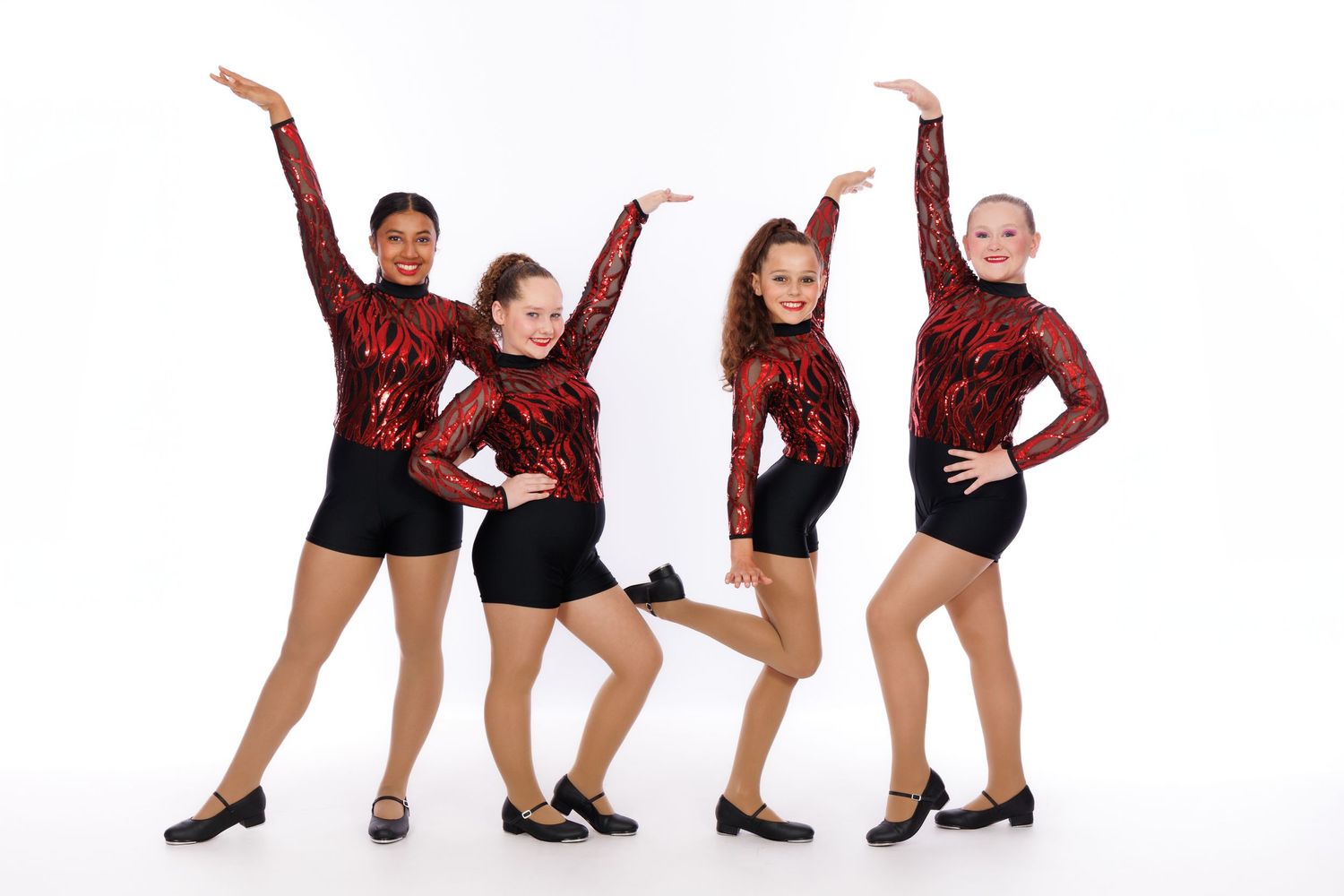Four dancers in red sequin costumes striking synchronized poses against white background.