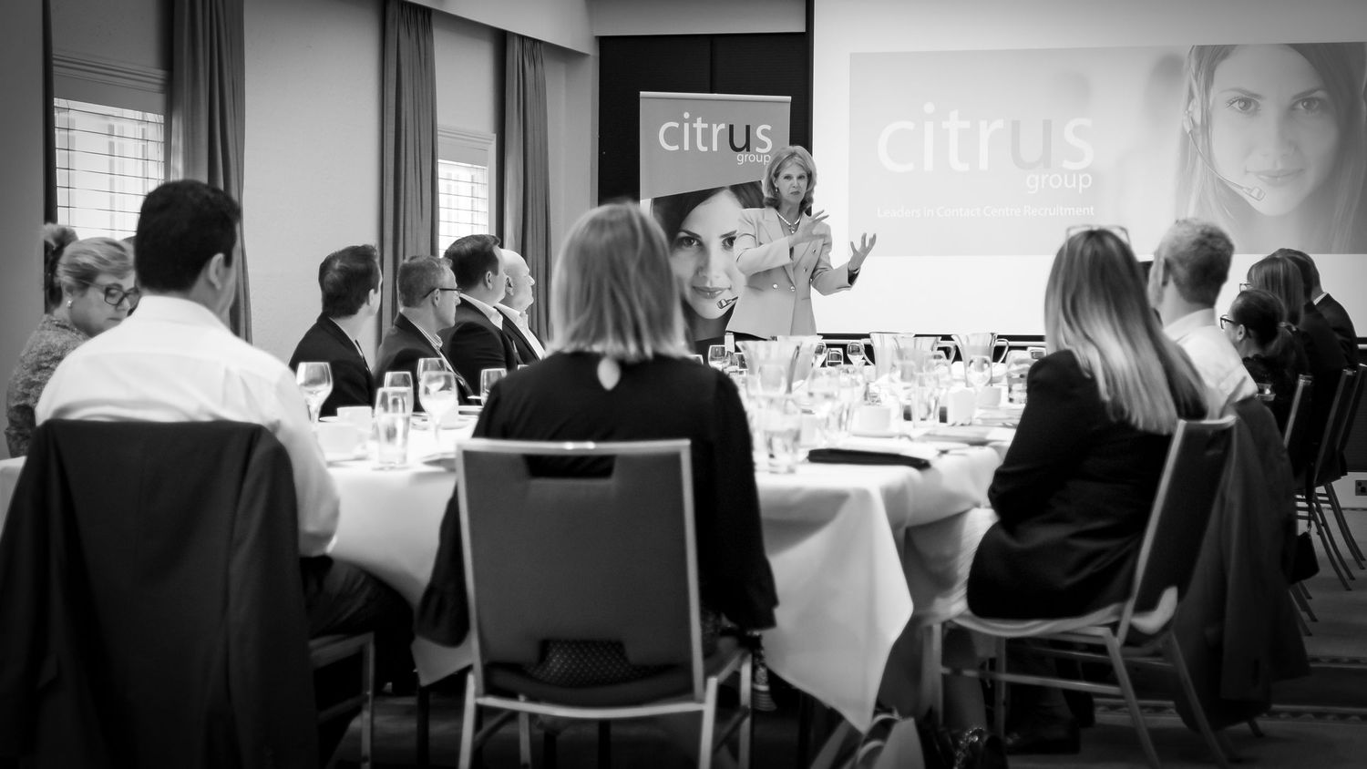 Sydney Event Photography - Business gathering in a conference room with white tablecloths and presentation screen.