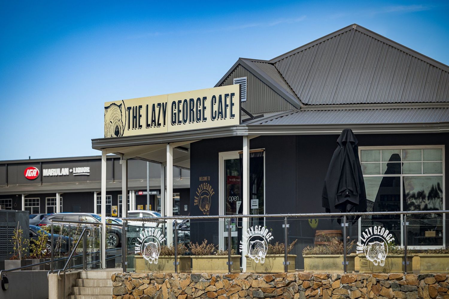 Modern cafe exterior with The Lazy George Cafe signage against blue sky.