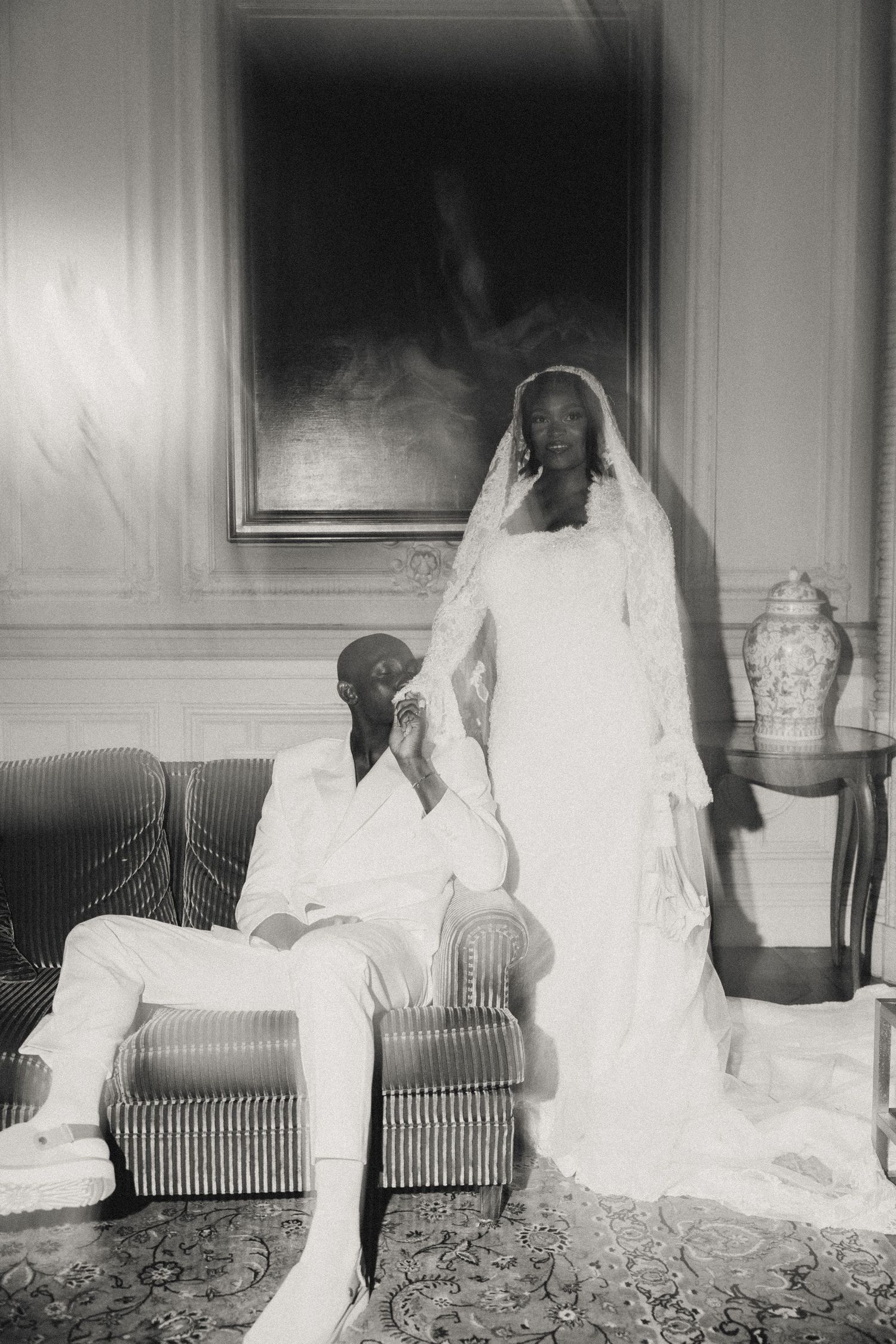 A series of vintage black and white photographs showing a figure in white clothing seated on a striped couch against a wall.