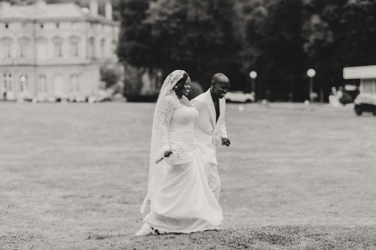 Black and white wedding photos show couple in romantic poses on a grassy lawn near a grand building.