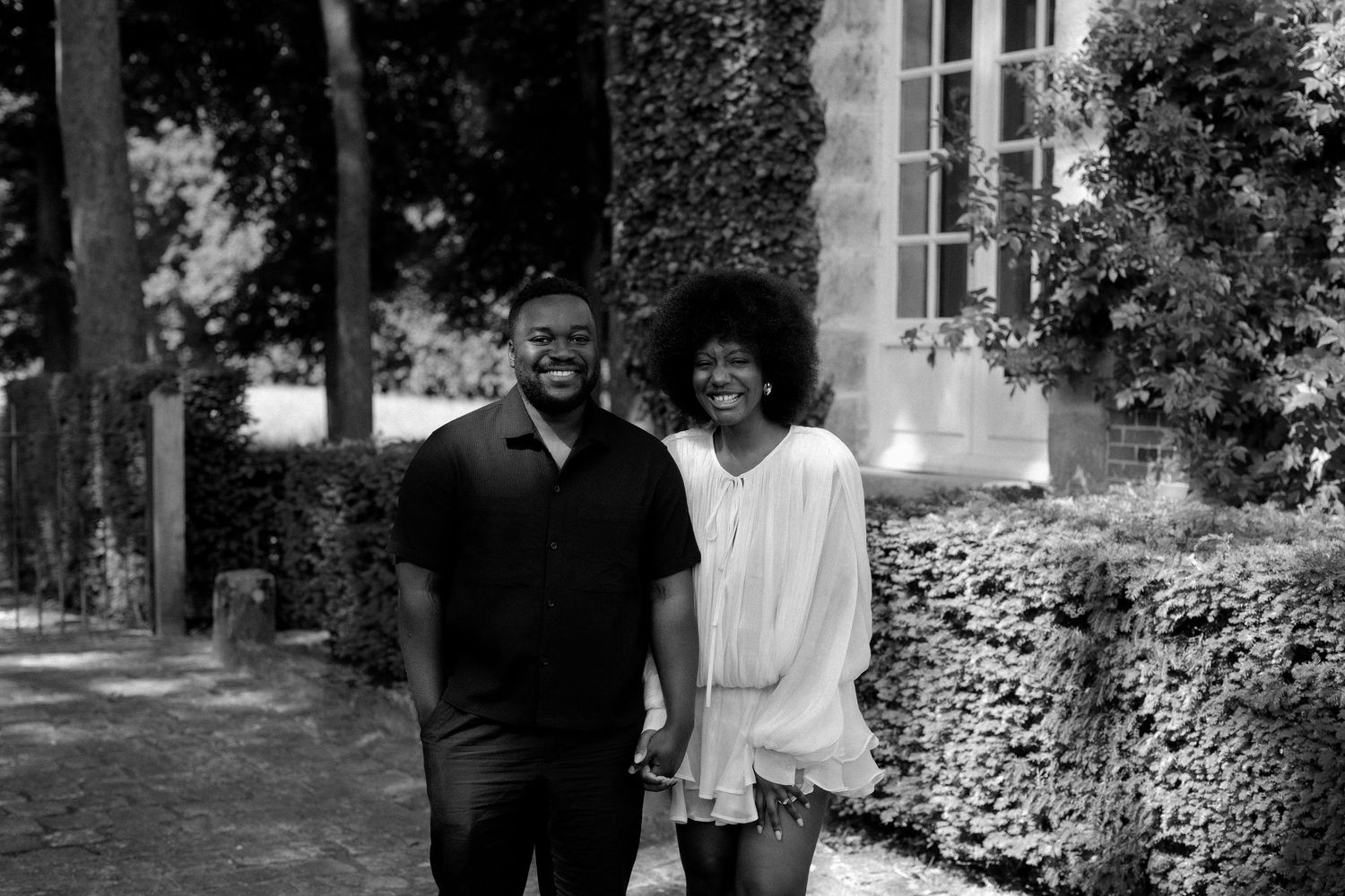Casual outdoor couple's photoshoot in front of ivy-covered building with natural lighting.