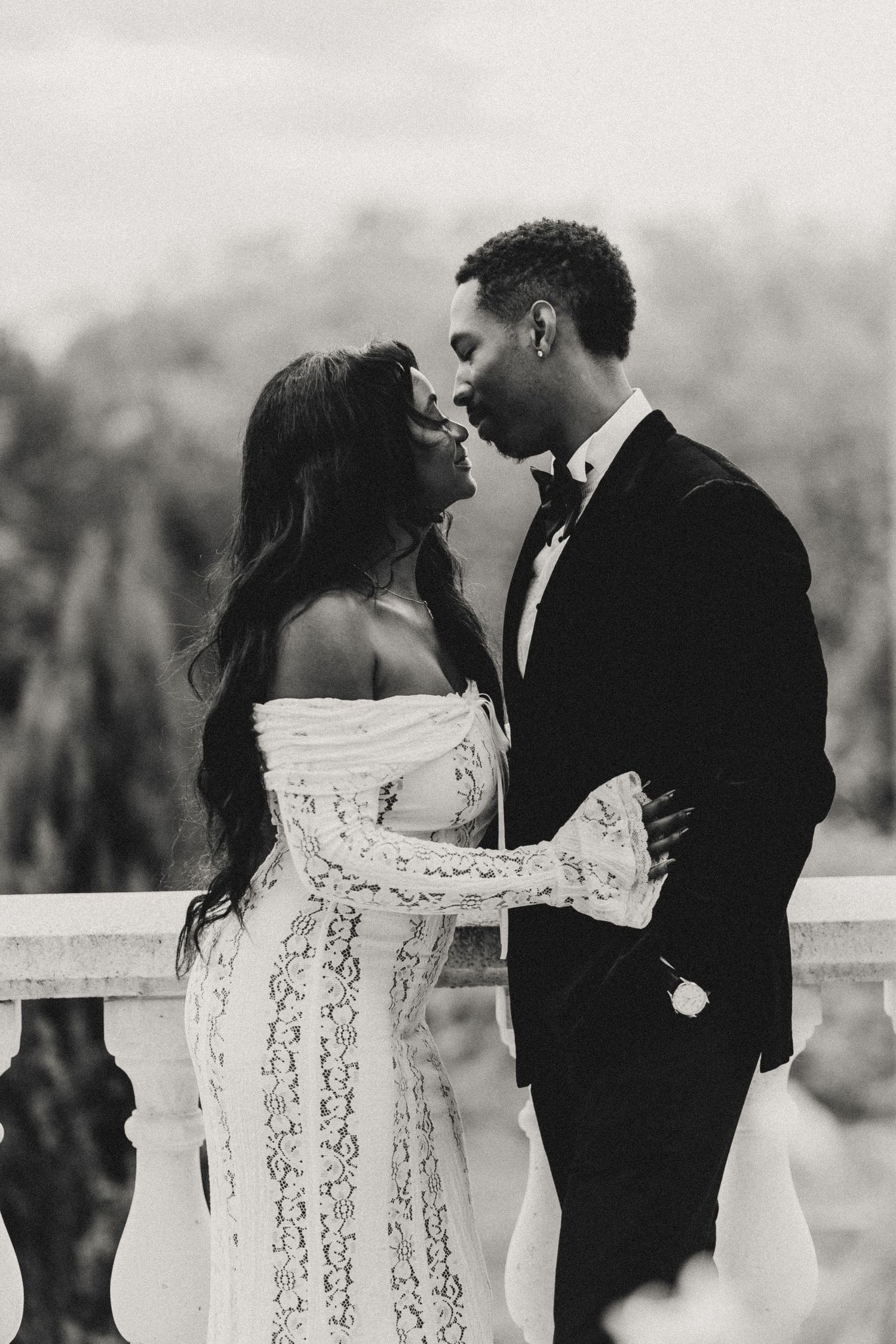 A romantic black and white photo series showing a couple in wedding attire embracing in an outdoor setting.