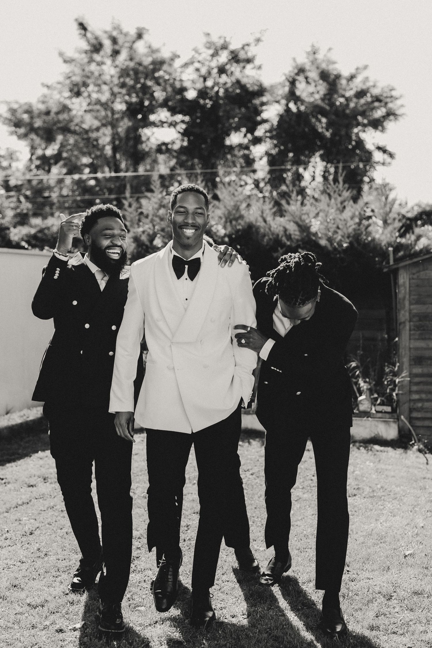 A group of friends laugh and smile together outdoors in a candid black and white photo series.