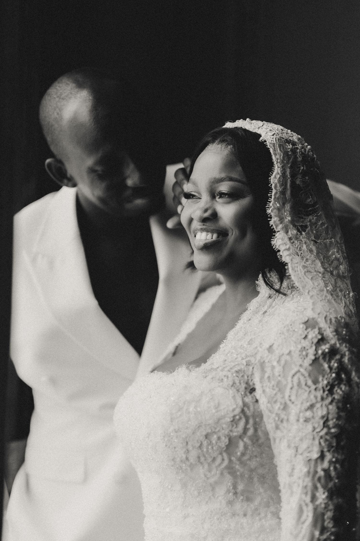 Black and white wedding portraits showing close-up details of a lace bridal veil and dress.