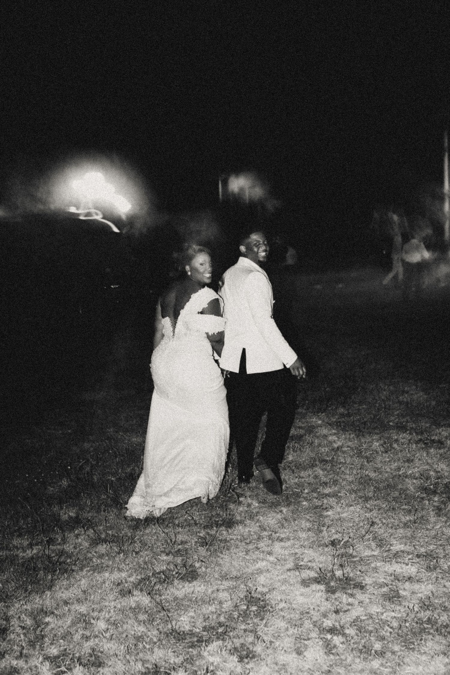 Dramatic nighttime wedding photos showing couple dancing in a dark outdoor setting.