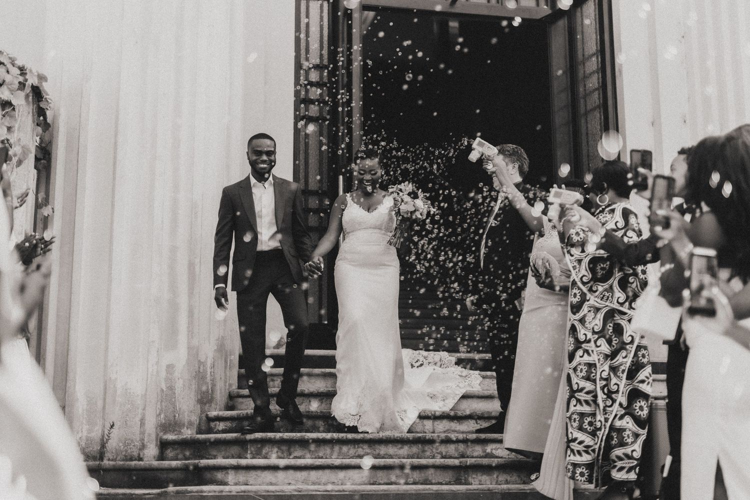 A couple exits their wedding ceremony while guests shower them with confetti.
