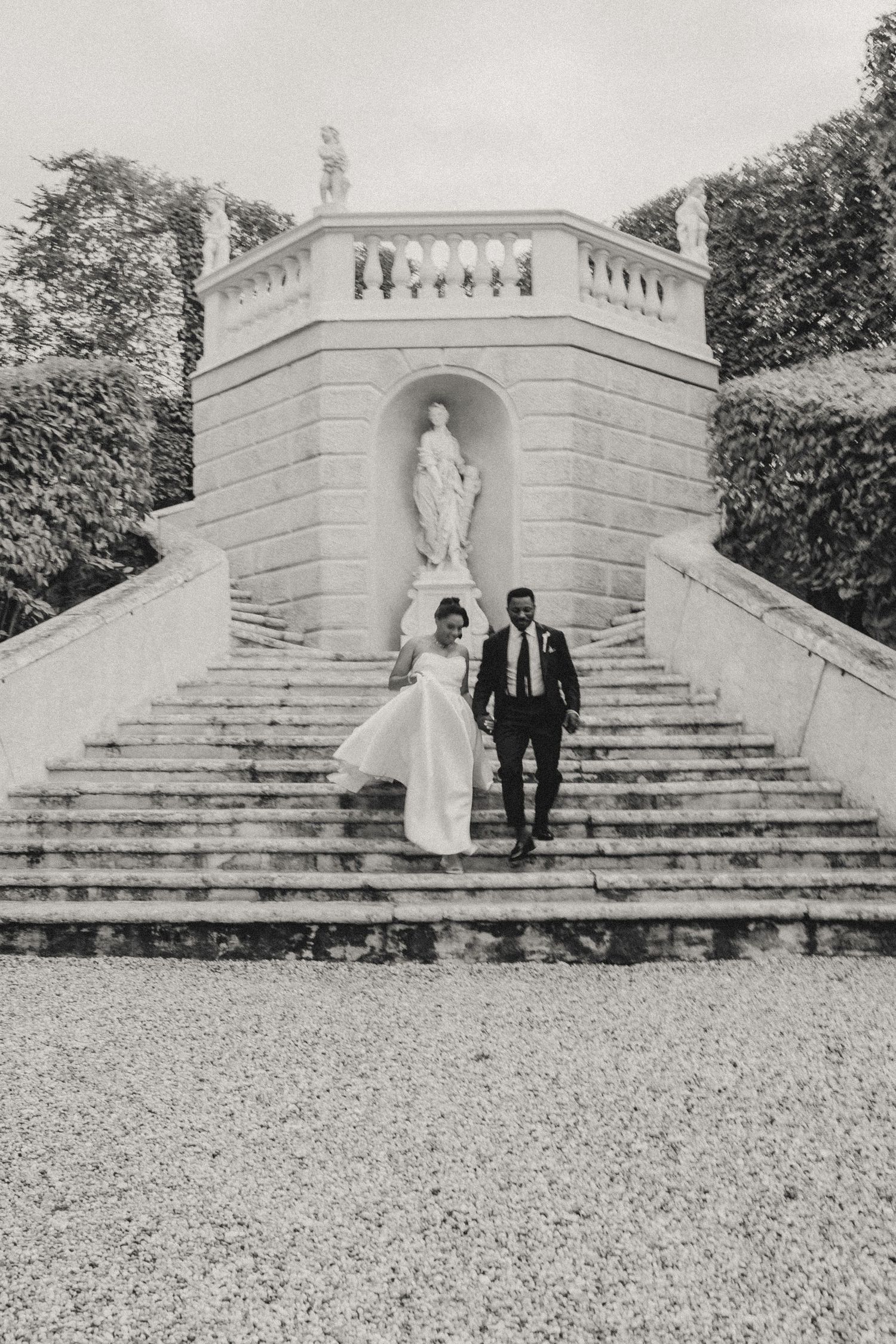 A couple poses on grand stone stairs in black and white wedding photos showing different angles and moments.
