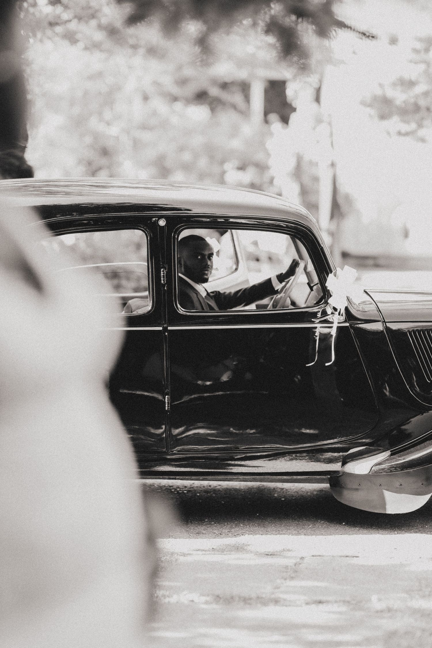 Classic black vintage car photographed from the side in a monochrome setting.