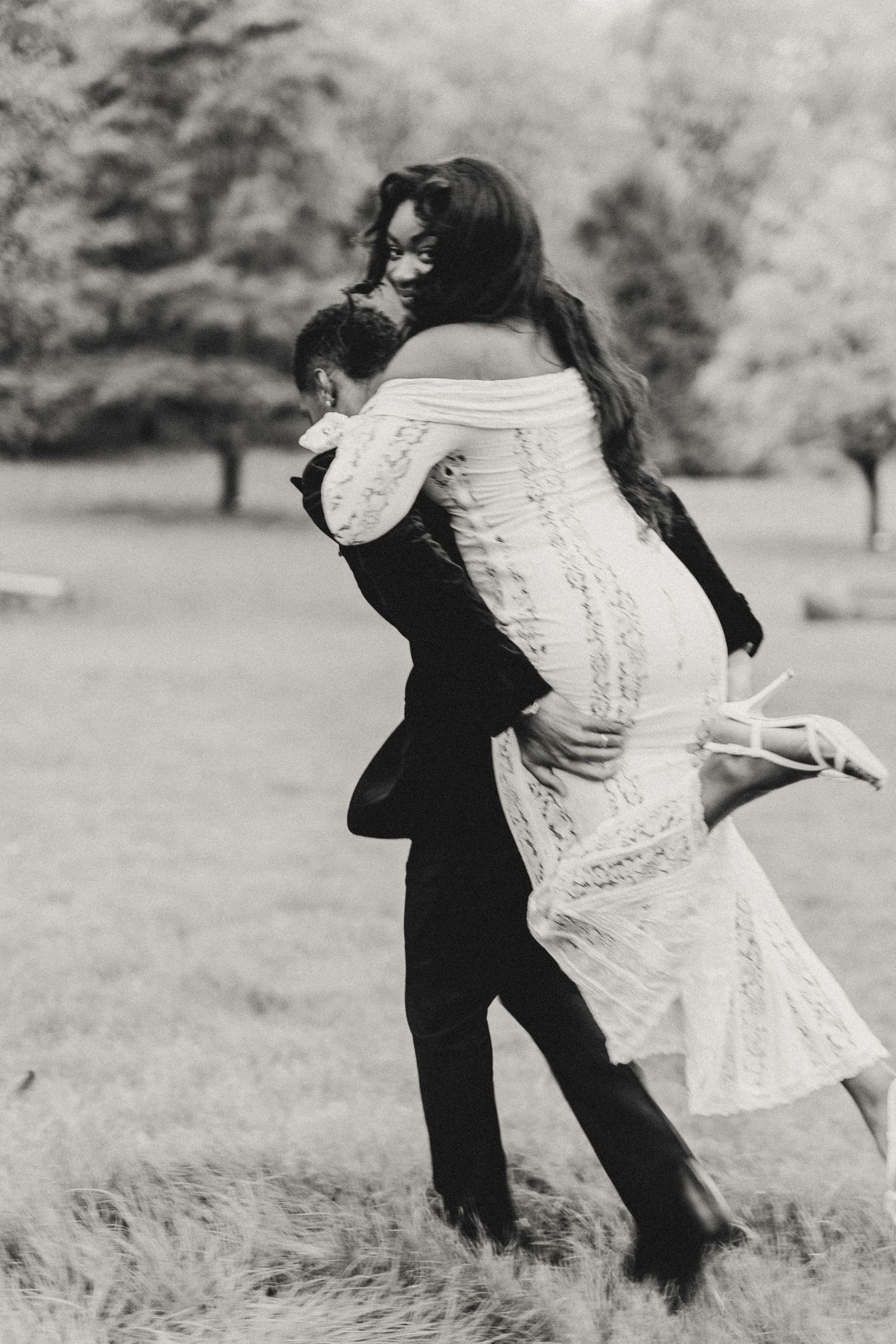A black and white photo series showing a couple dancing and spinning together in a grassy field.