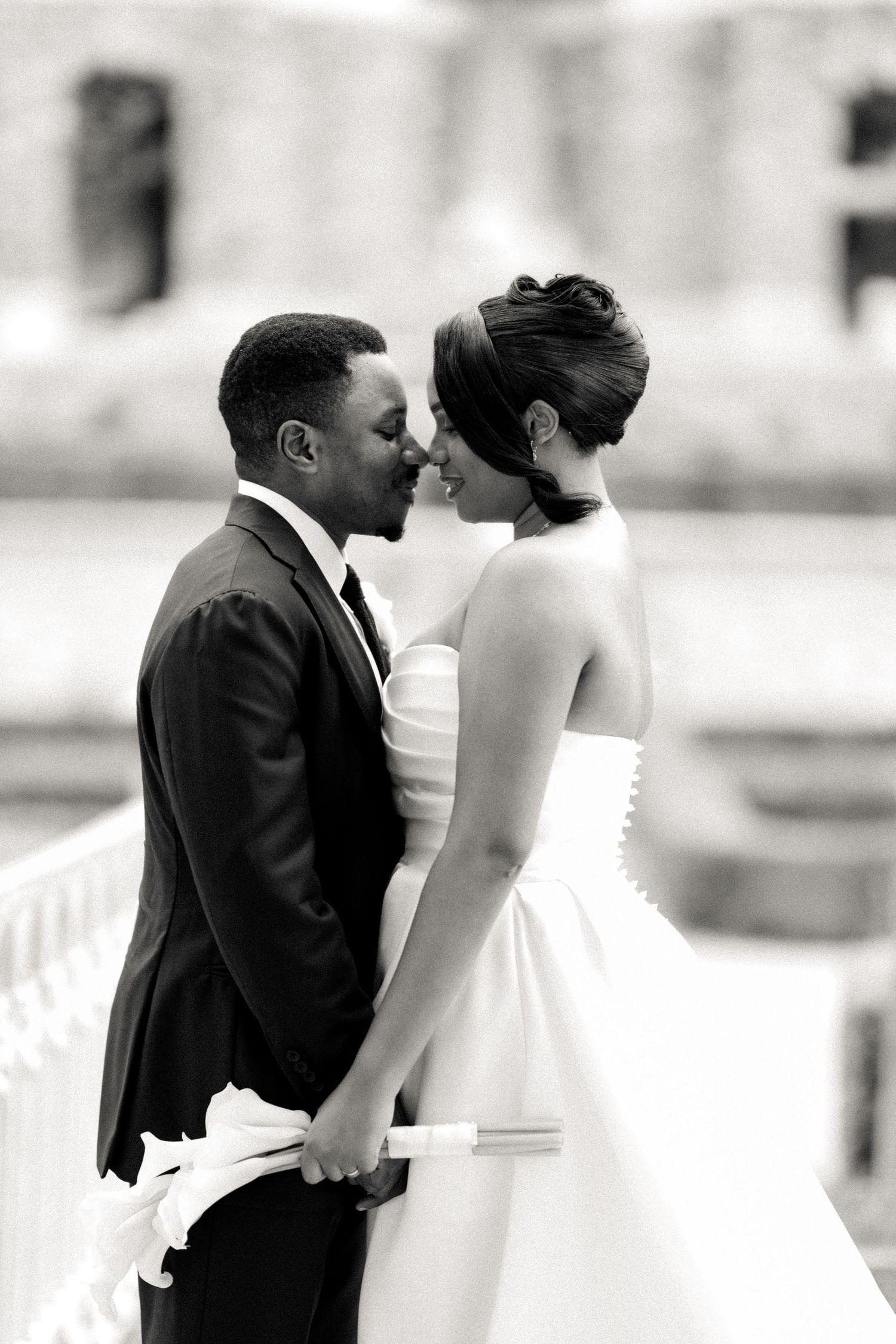 A black and white wedding photo captures a tender moment between newlyweds on their special day.