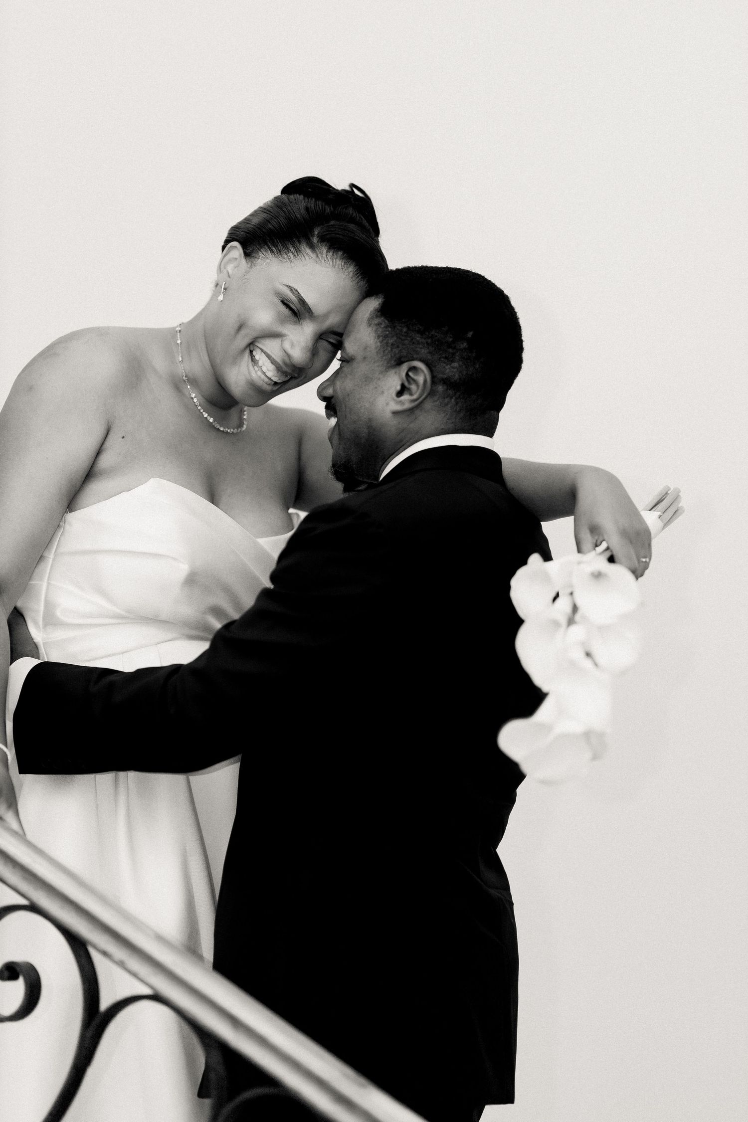 A romantic black and white portrait shows a couple in formal attire sharing an intimate moment.