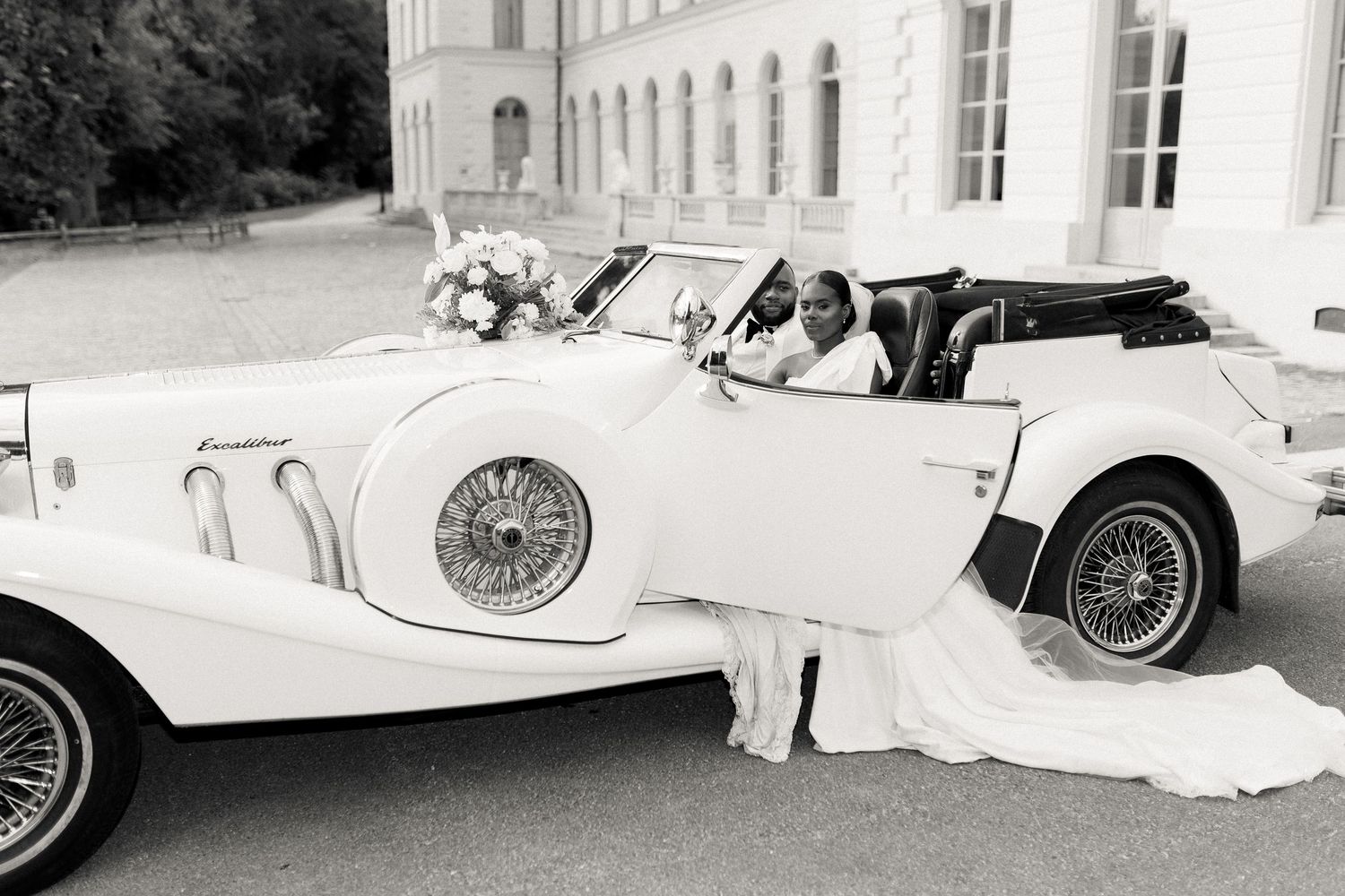 Vintage black and white photograph of classic luxury cars parked in front of an elegant European mansion.