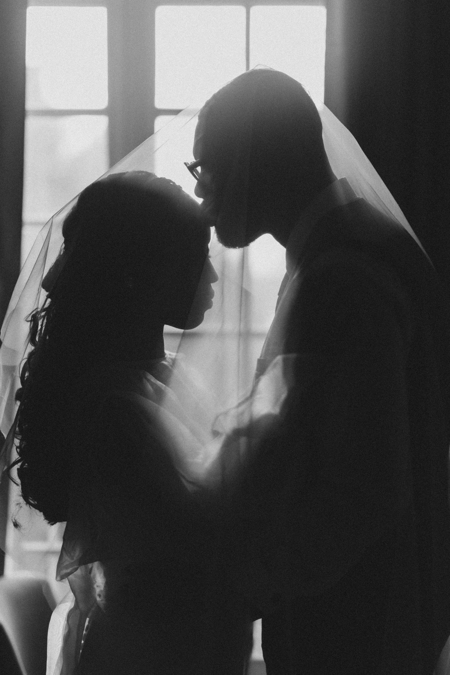 Black and white silhouettes of people in profile against bright windows create a dramatic contrast in lighting.
