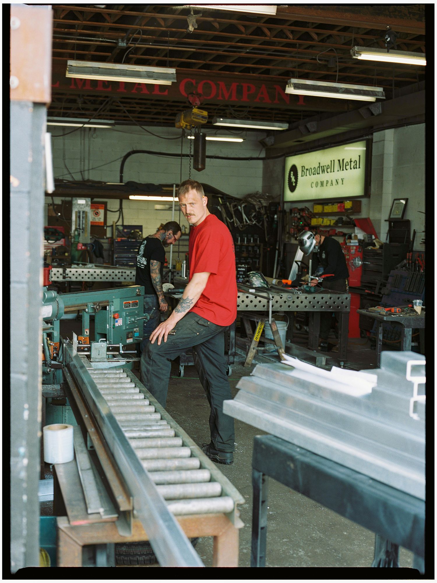 Worker in red shirt stands in Broadwell Metal Company industrial fabrication shop.