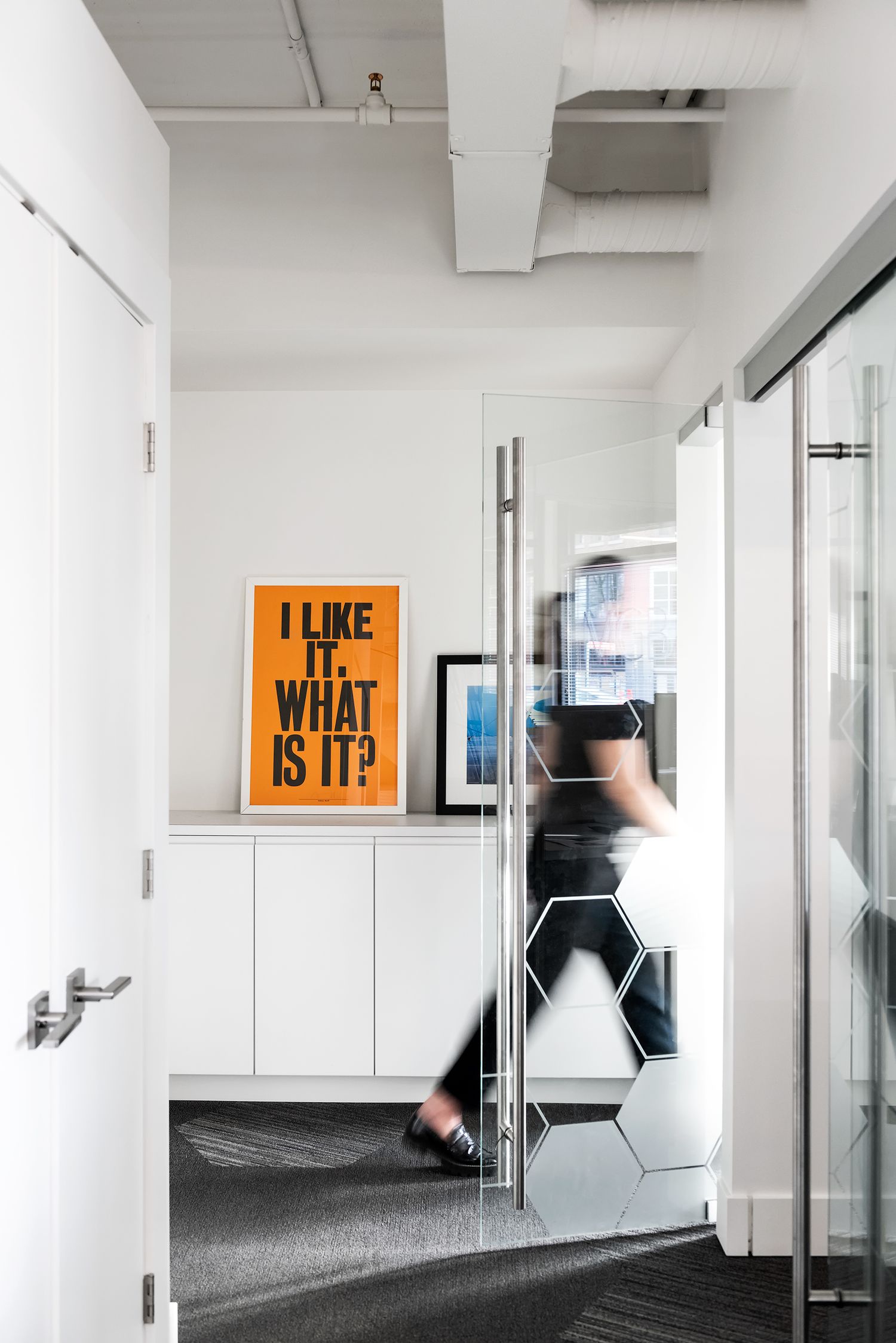 Modern office hallway with orange motivational poster and blurred person in motion.