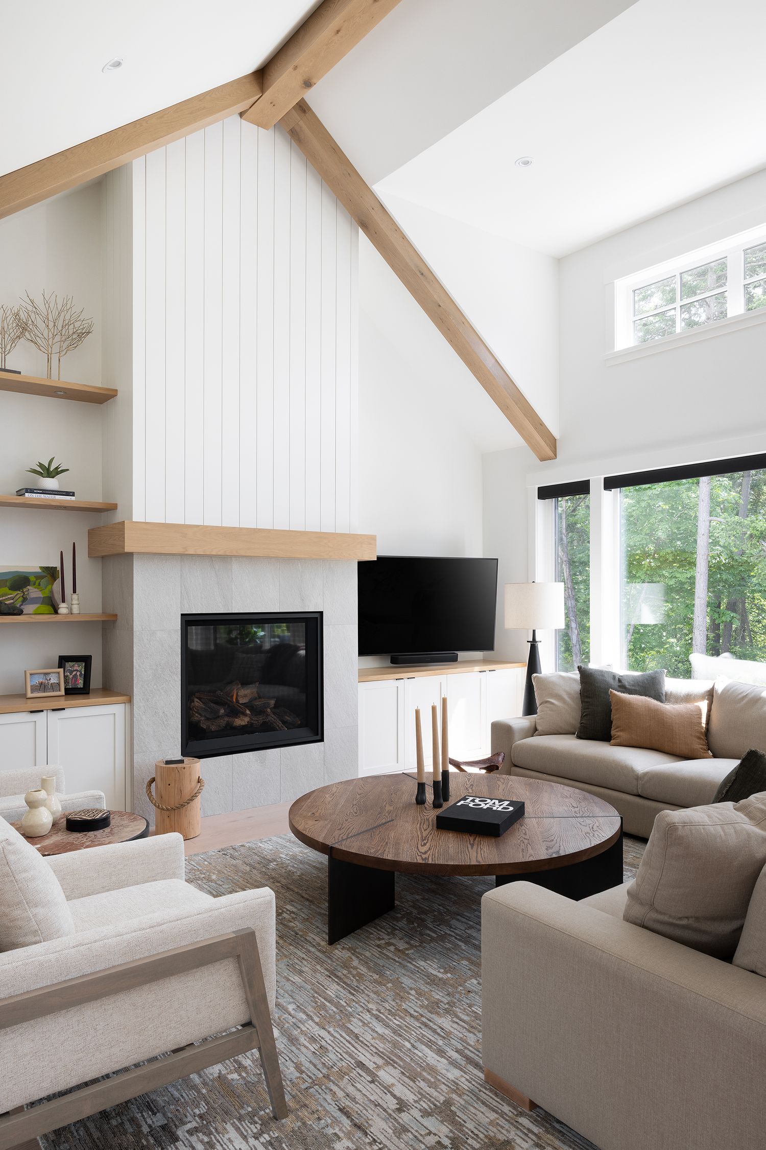 Bright living room with vaulted ceiling, exposed wood beams, shiplap fireplace wall, and neutral upholstered furniture.
