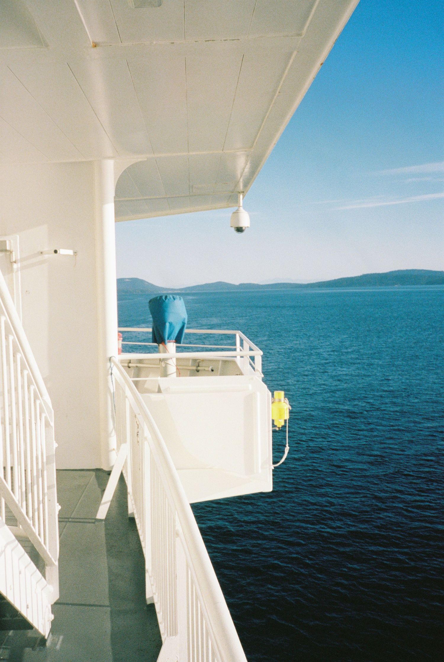 View from BC Ferries deck overlooking calm blue ocean water with distant mountains.