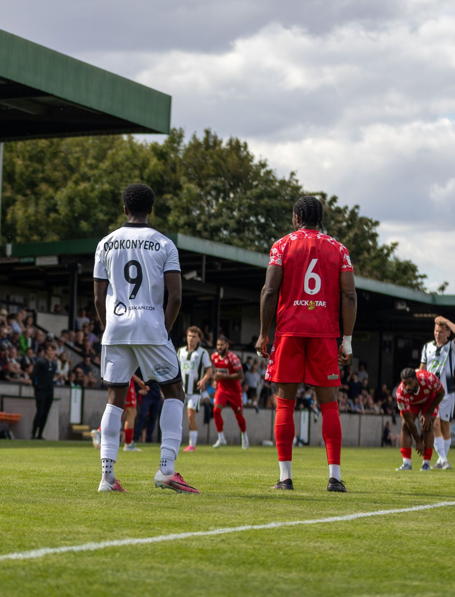 Player number 9 Ogokonyero in white faces number 6 in red during a football match.