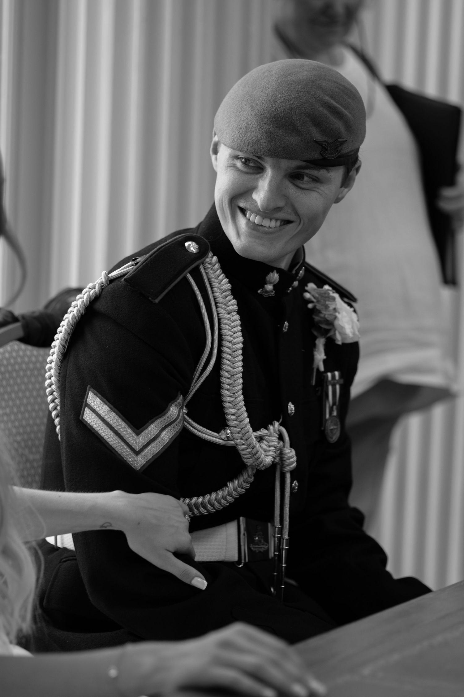 Smiling military officer in dress uniform with beret and medals signing documents at wedding.
