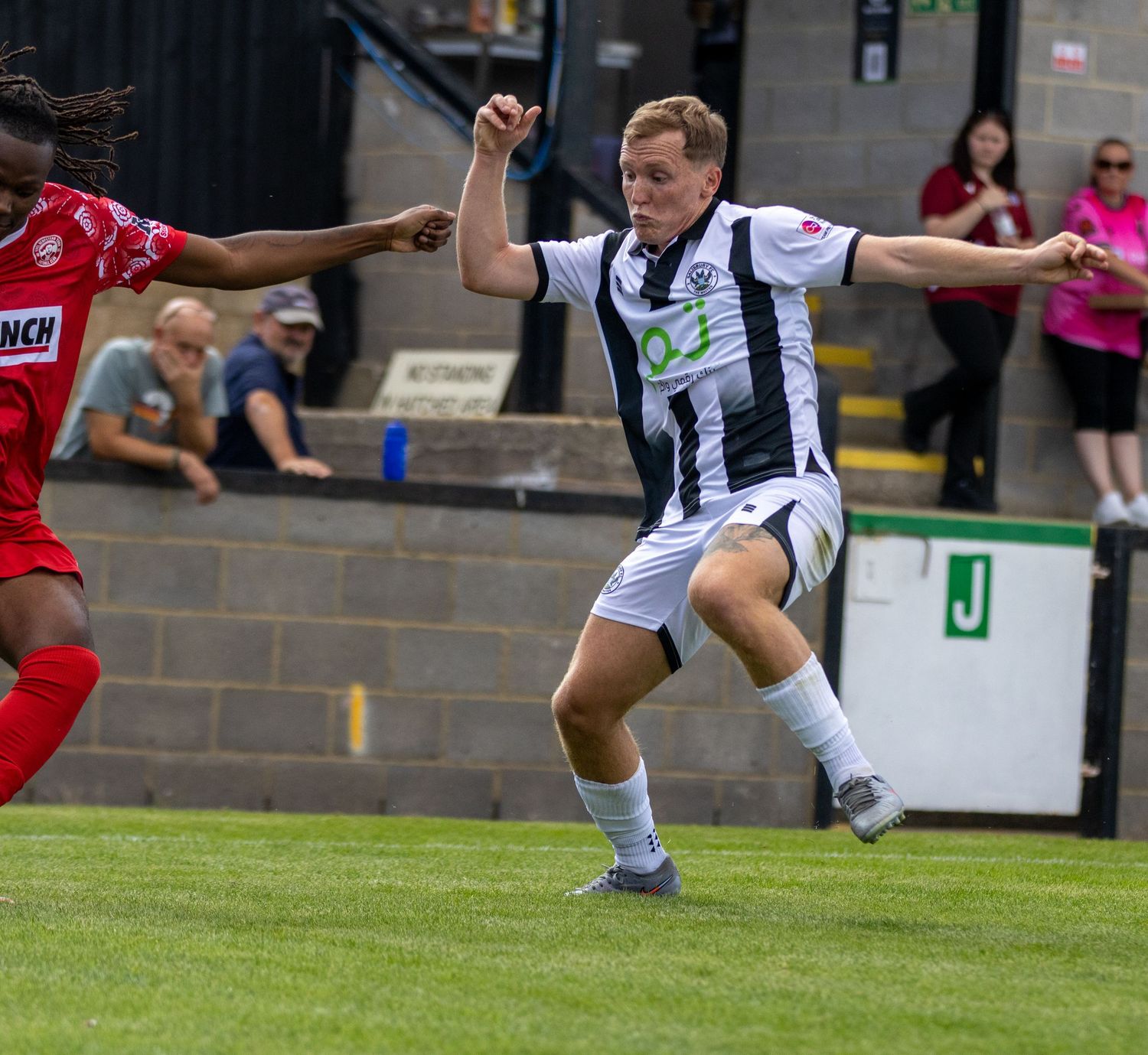 Two soccer players compete for the ball during an intense football match at a stadium.