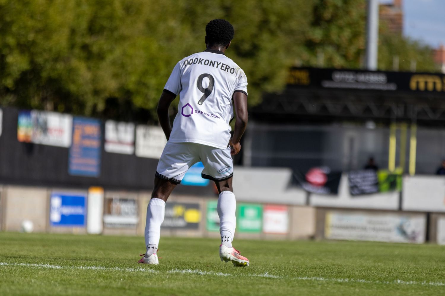 Player number 9 Asiedu Onyero runs in white football kit during outdoor match.