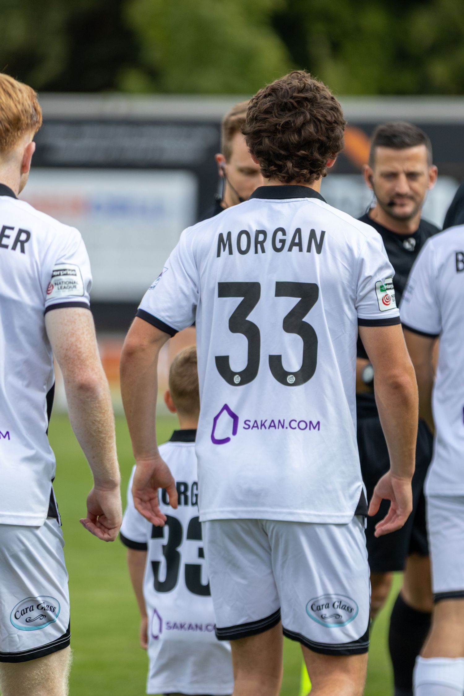 Football player Morgan wearing number 33 white Sakan.com sponsored shirt walking on the pitch.
