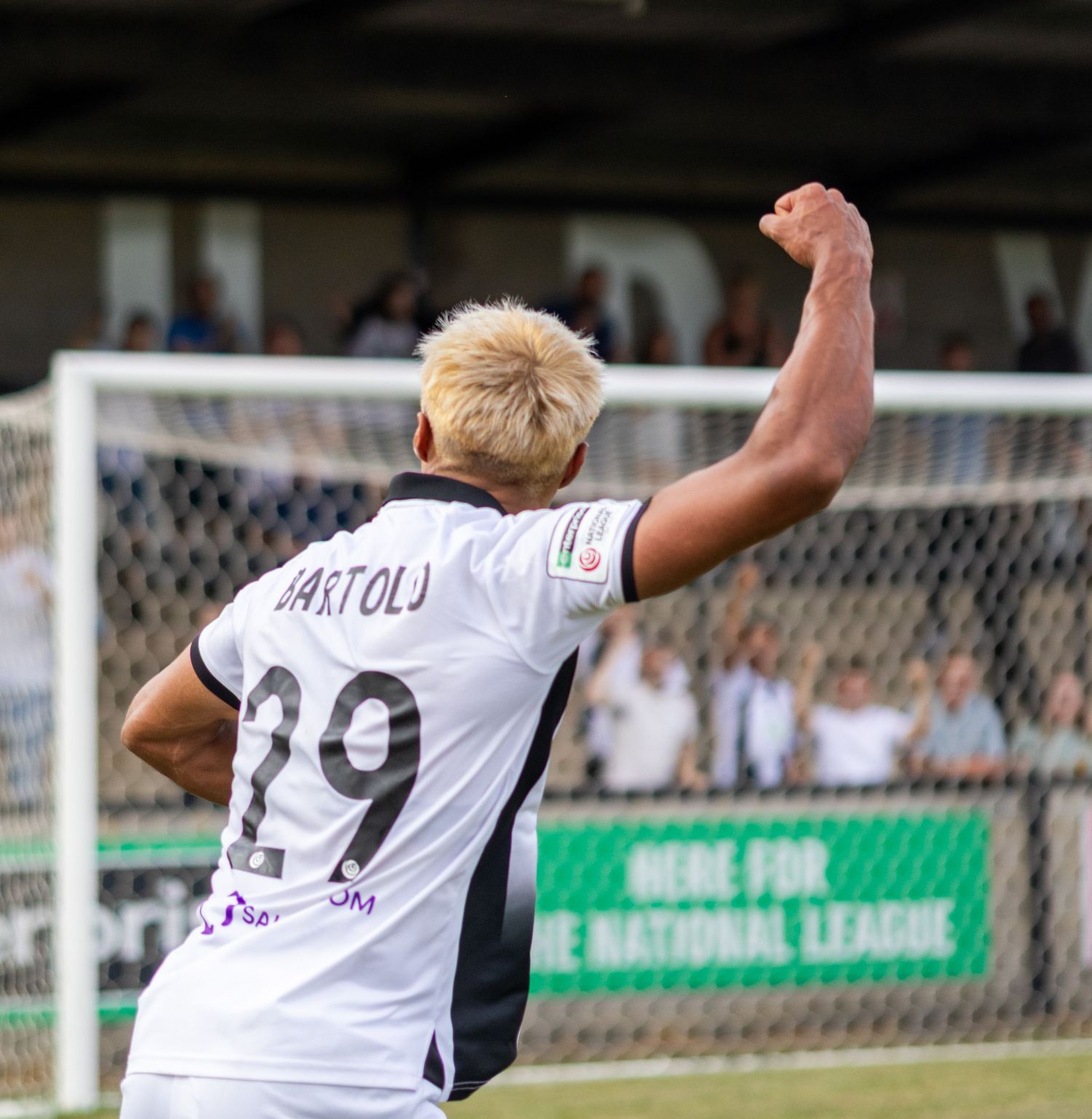 Soccer player Bartoli number 29 in white uniform celebrates with fist raised near goal.