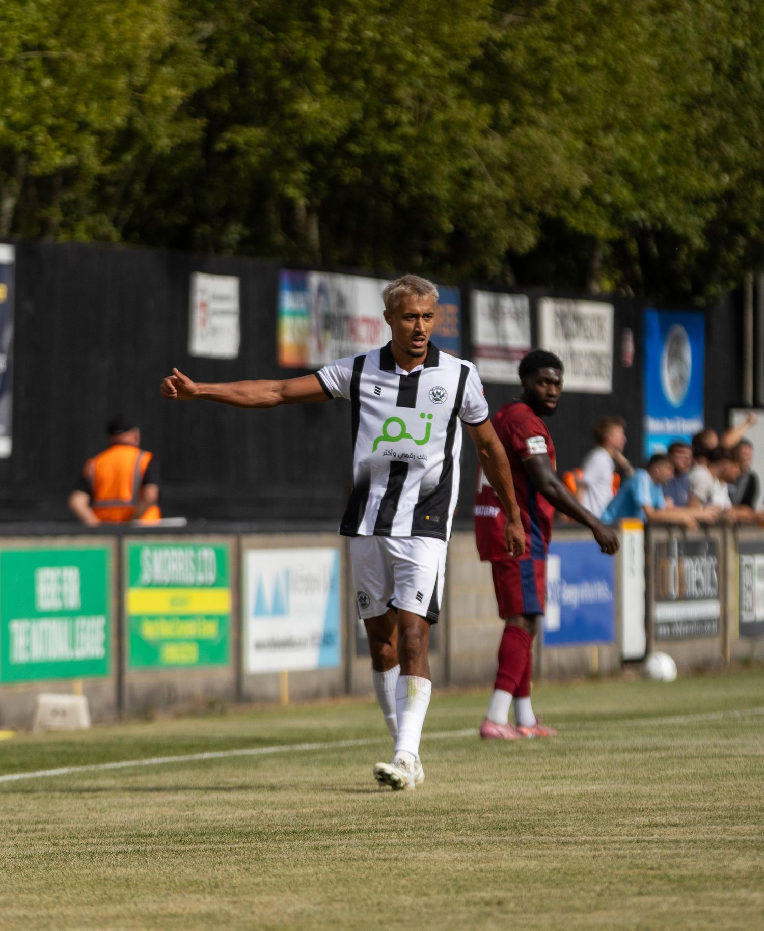 Salisbury FC player in black and white kit gestures during a sunny non-league football match.