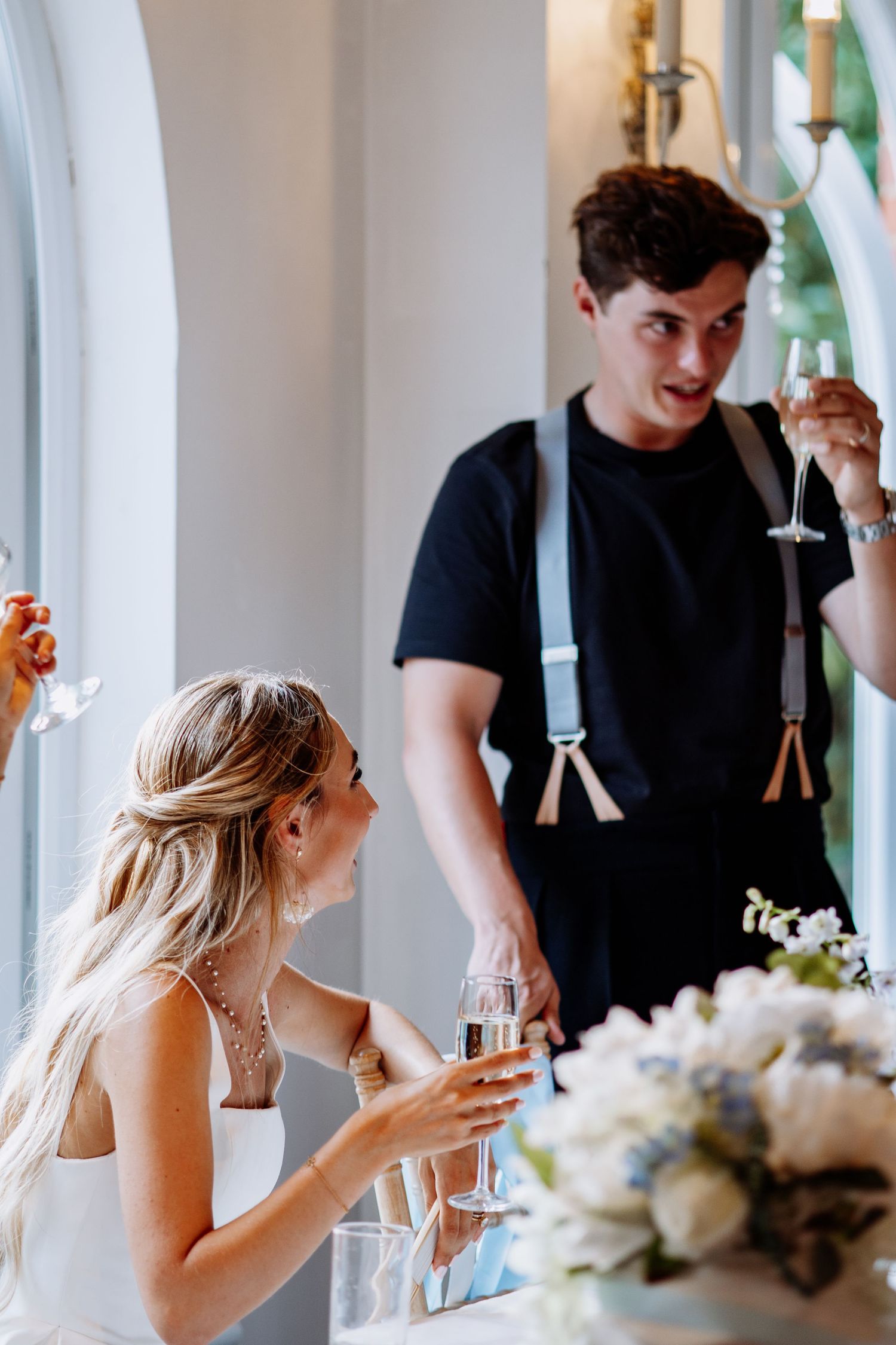 Bride and guest toasting with champagne glasses at elegant wedding reception.