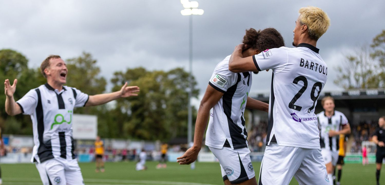 Soccer players in black and white uniforms celebrate a goal, with player Bartoli number 29 prominent.