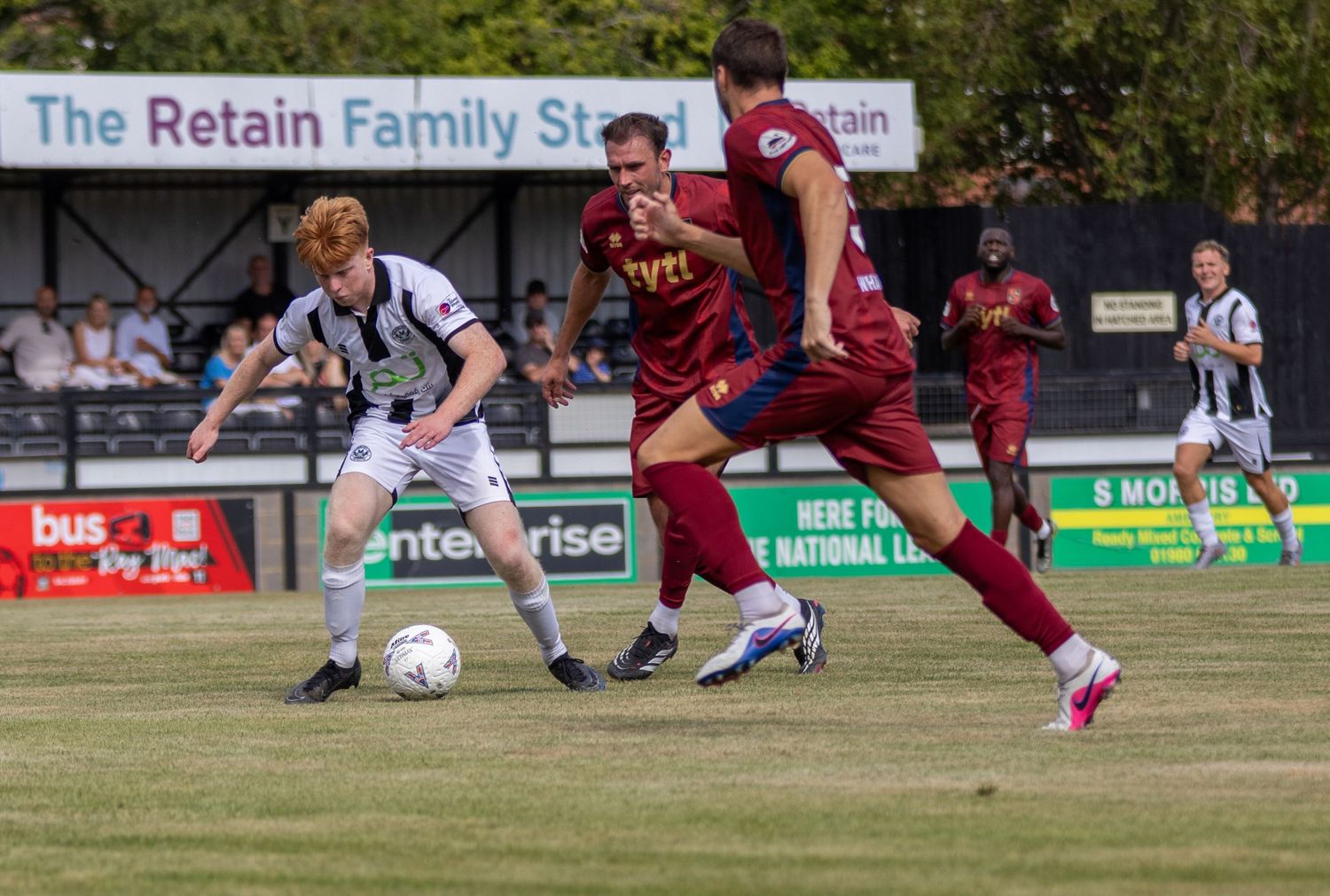 Salisbury FC players in black and white challenge opponents in maroon during a competitive football match.