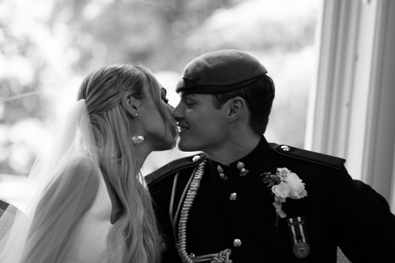 Bride and groom share first kiss in black and white wedding photo.