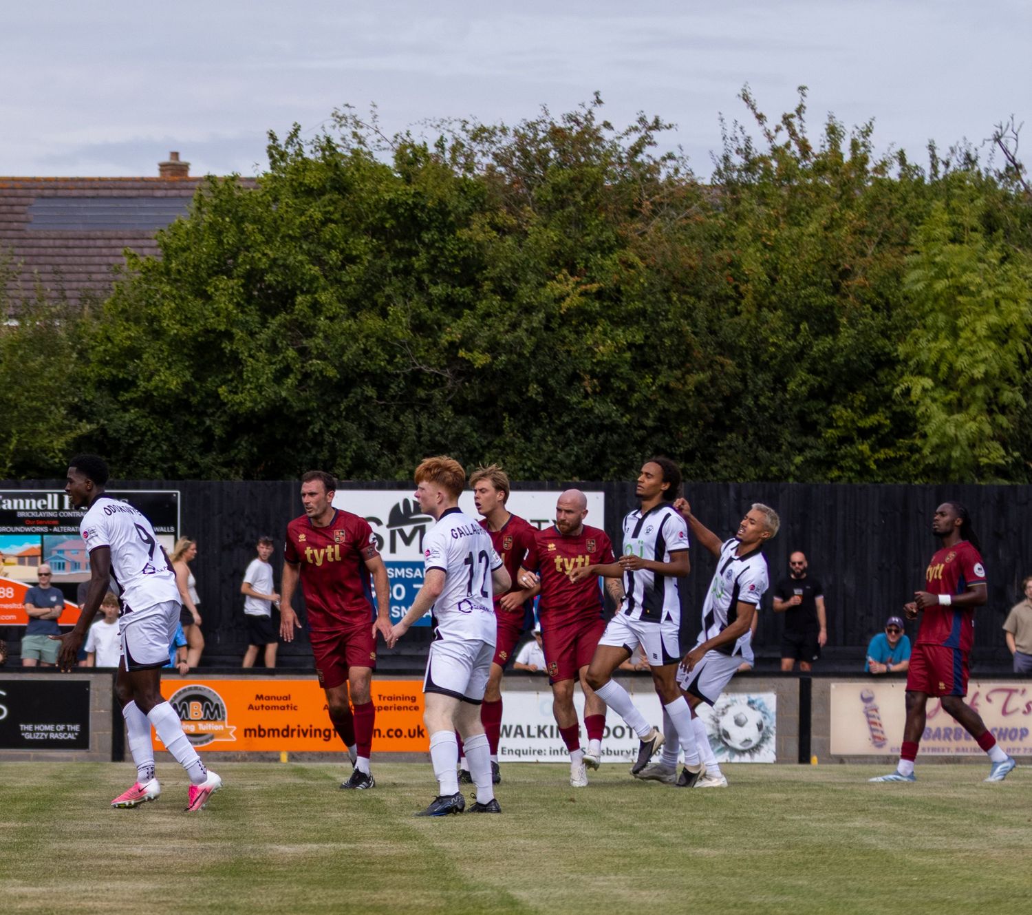 Salisbury FC players in white compete against opponents in a crowded penalty area during a match.