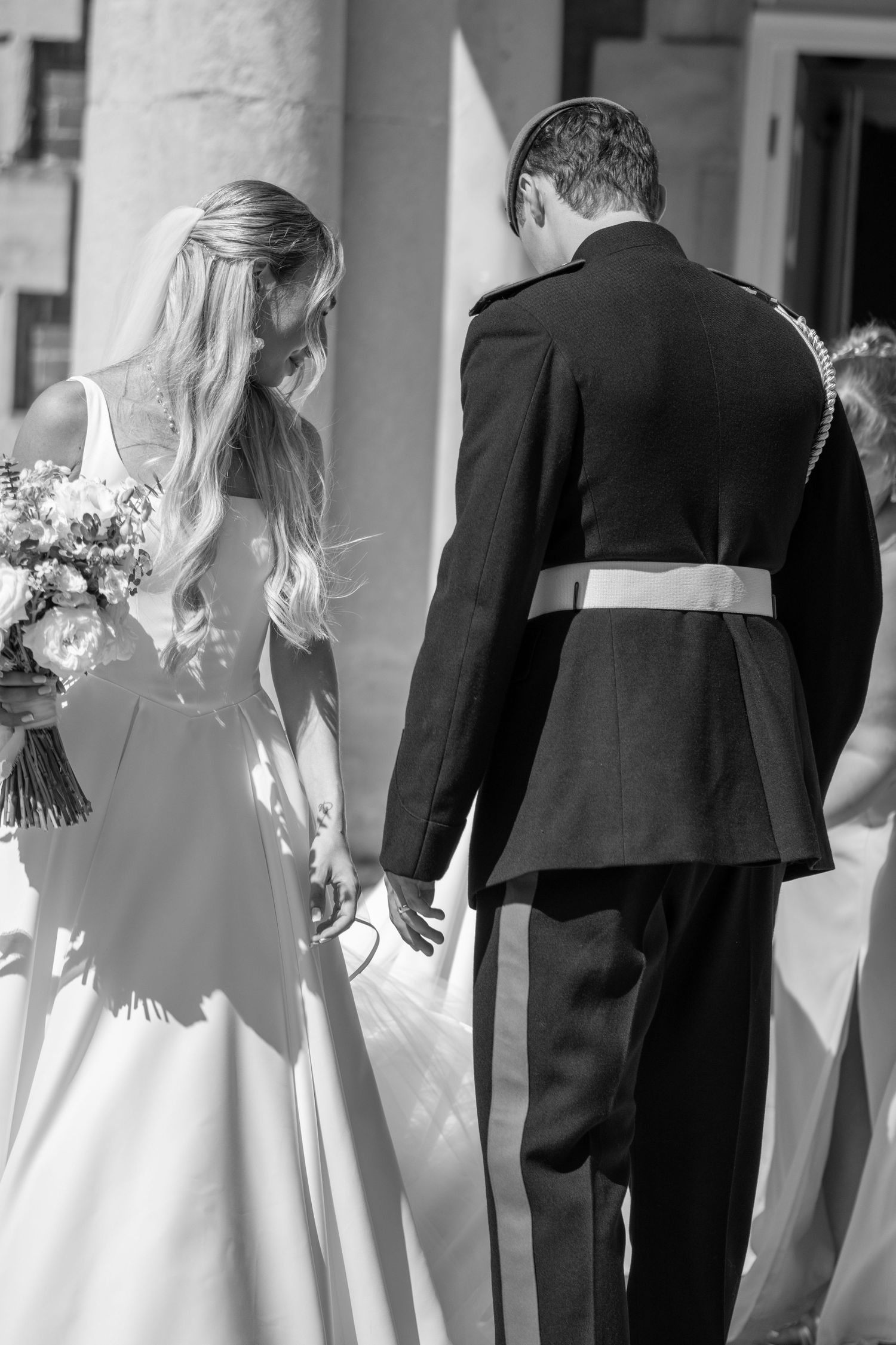 Bride and groom walking hand in hand, viewed from behind at wedding.