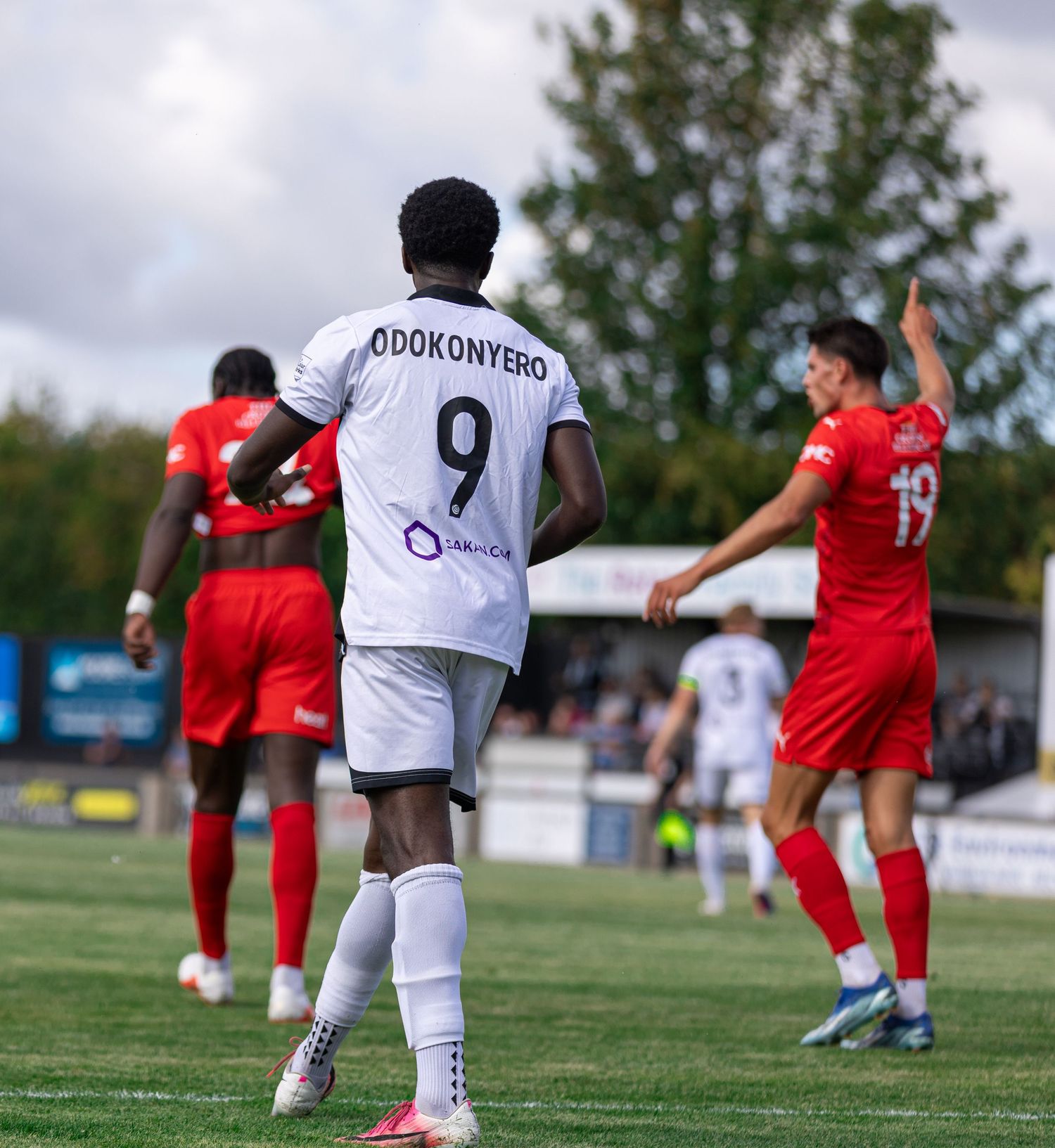 Soccer player Odokonyero wearing number 9 white jersey stands on green pitch during a competitive match.