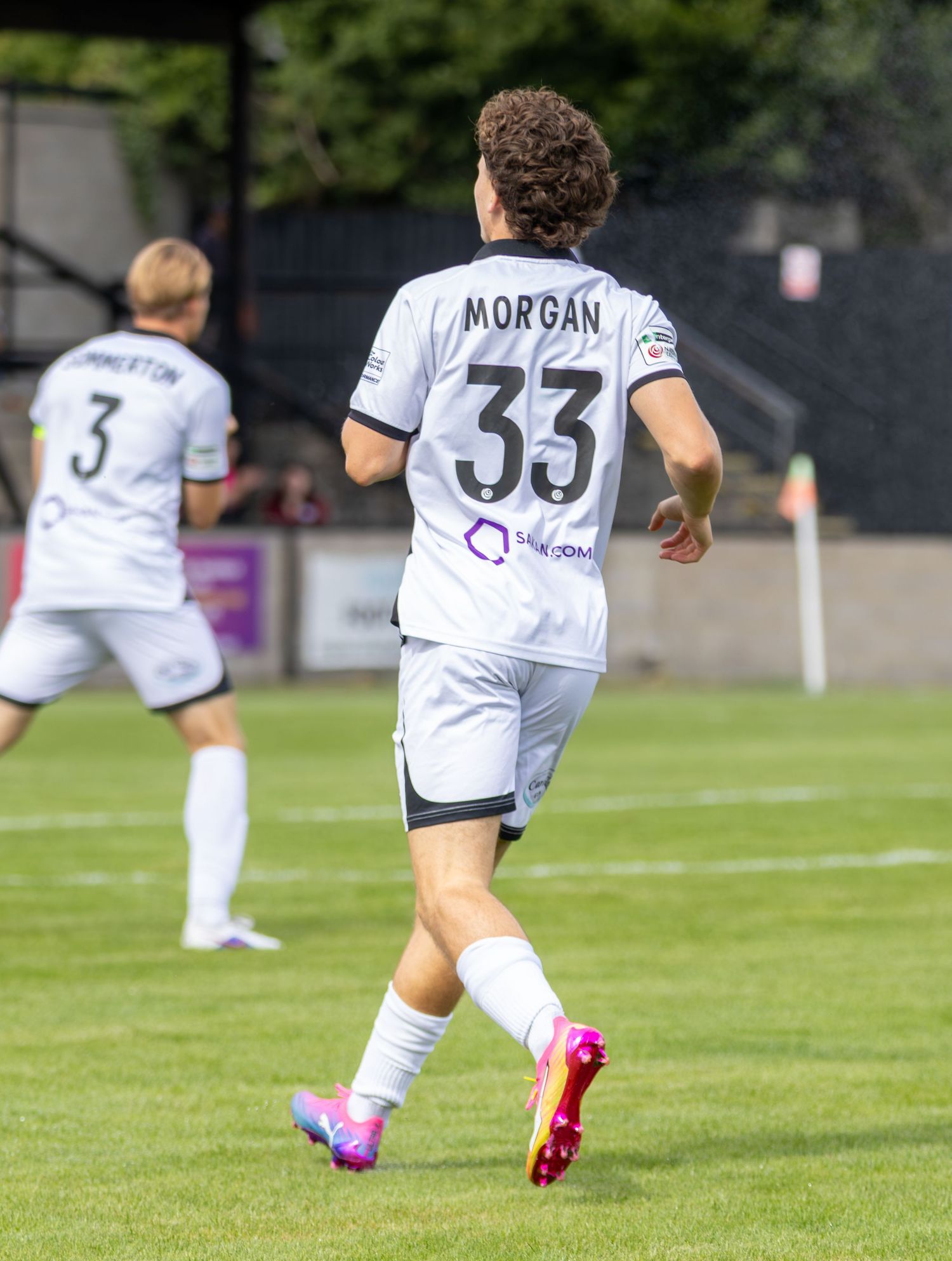 Soccer player Morgan wearing number 33 white jersey runs on the pitch during a football match.