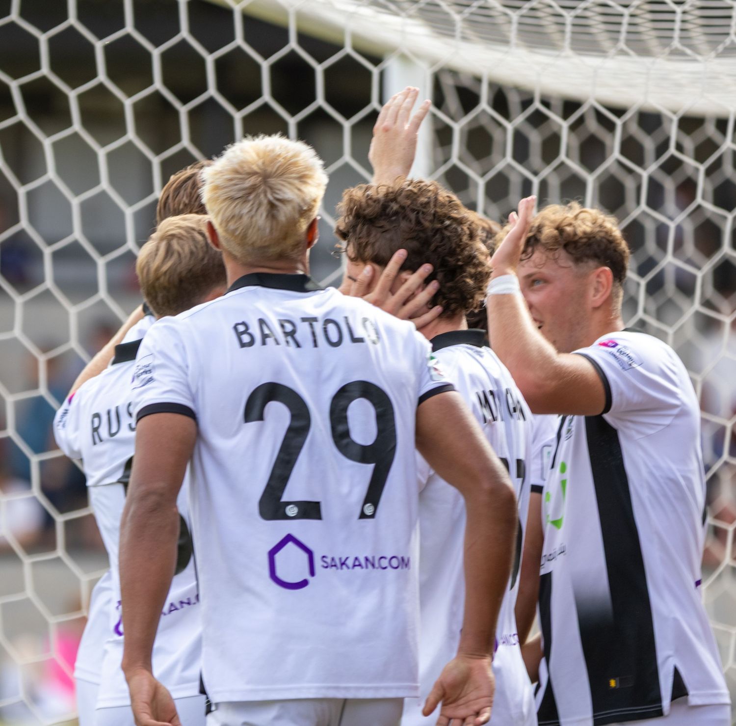 Soccer players in white uniforms celebrate together, with player Bartoli number 29 visible.