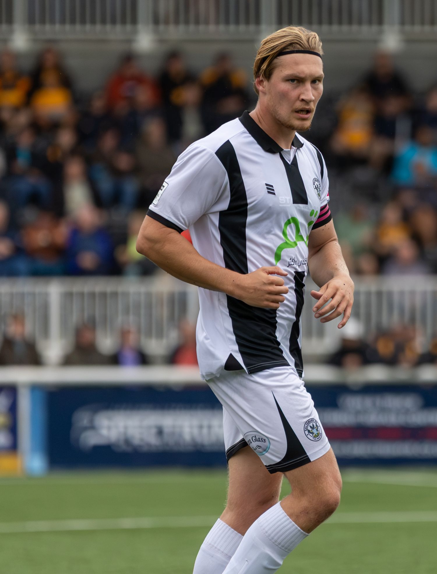 Soccer player in white and black kit running on field during a match.