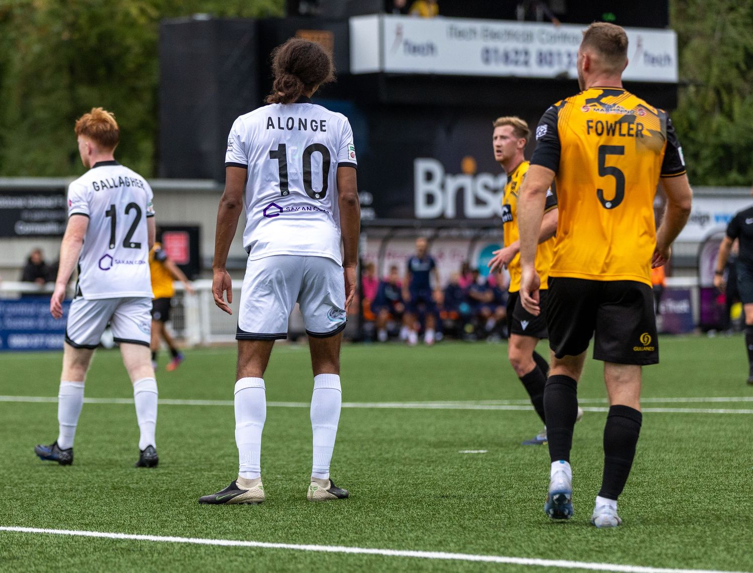 Soccer players in white and yellow kits, including Alonso #10 and Fowles #5, walk on a green pitch during a match.