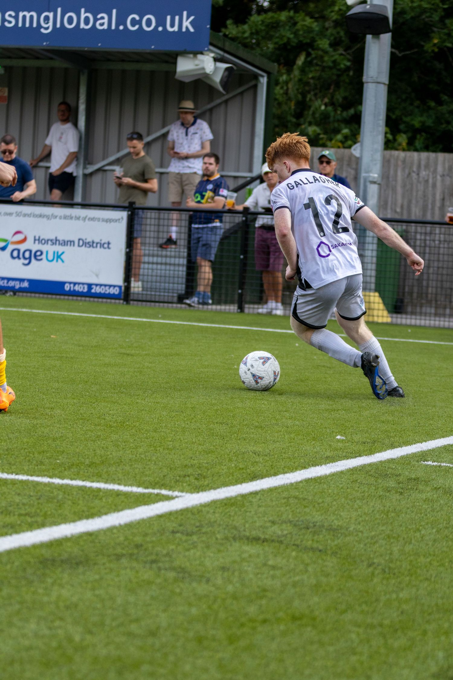 Gallagher number 12 in white kit prepares to cross the ball from the corner during a football match.