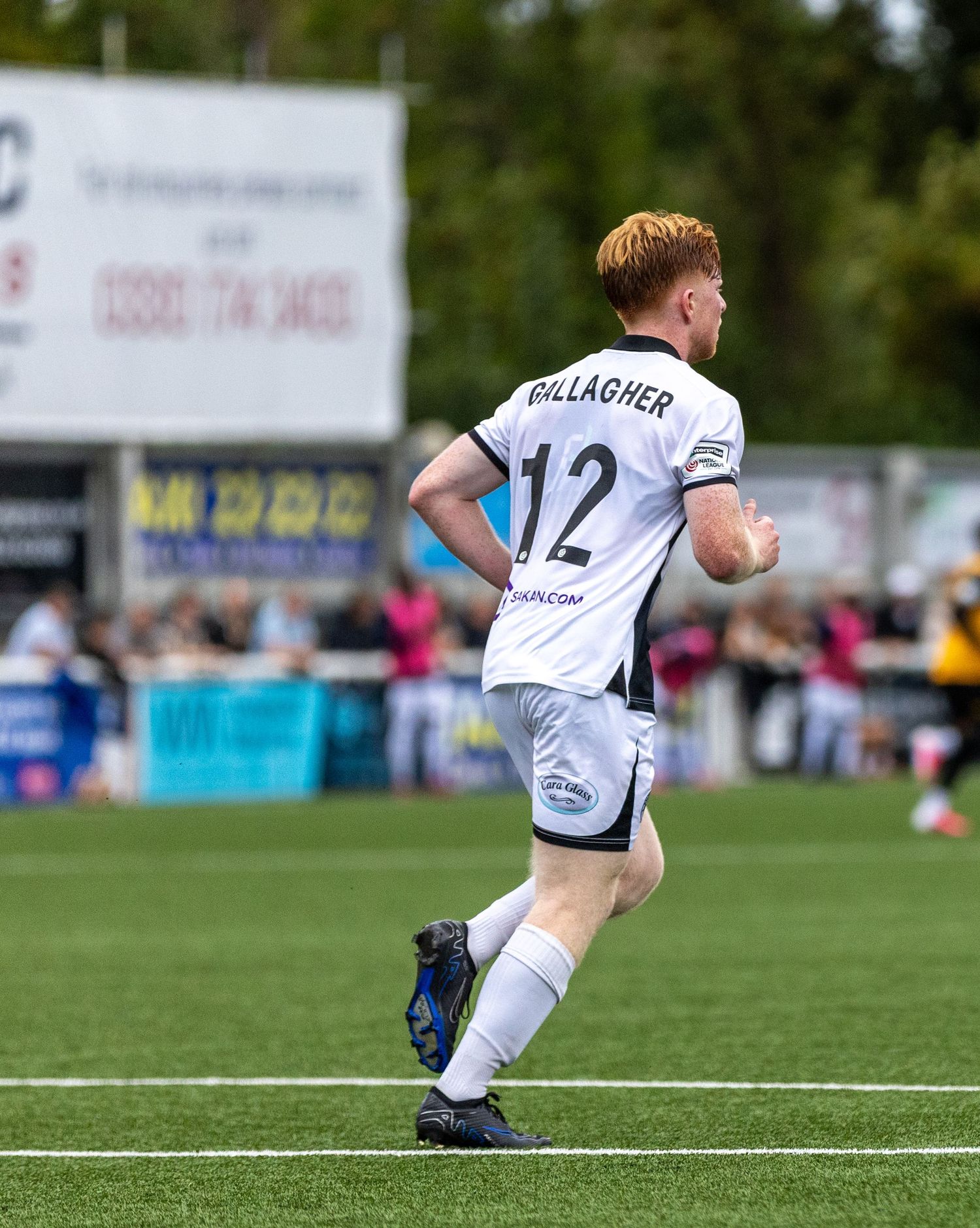 Soccer player Gallagher wearing number 12 white jersey runs on green pitch during a match.
