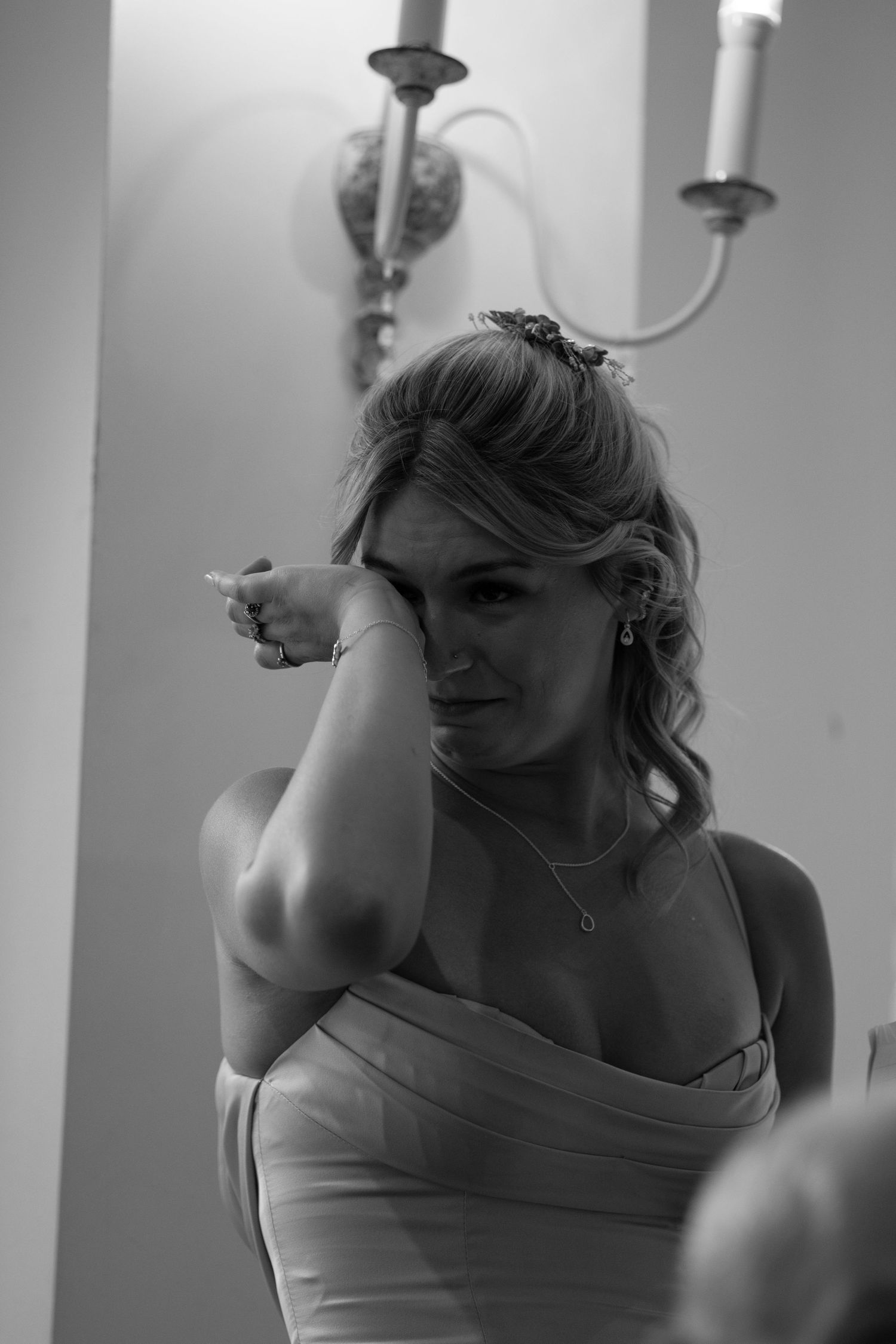 Black and white photo of emotional bridesmaid wiping tears at wedding ceremony.