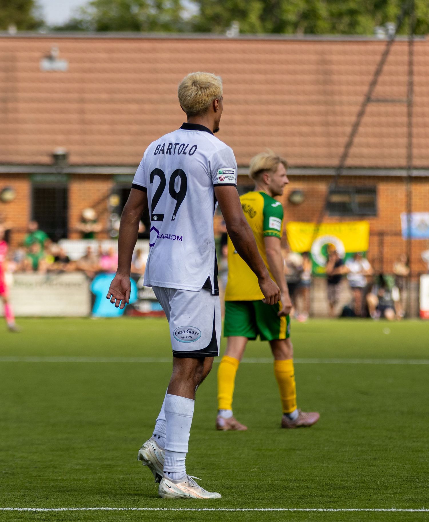 Bartolo wearing number 29 white kit walks on the pitch during a match against a yellow and green team.