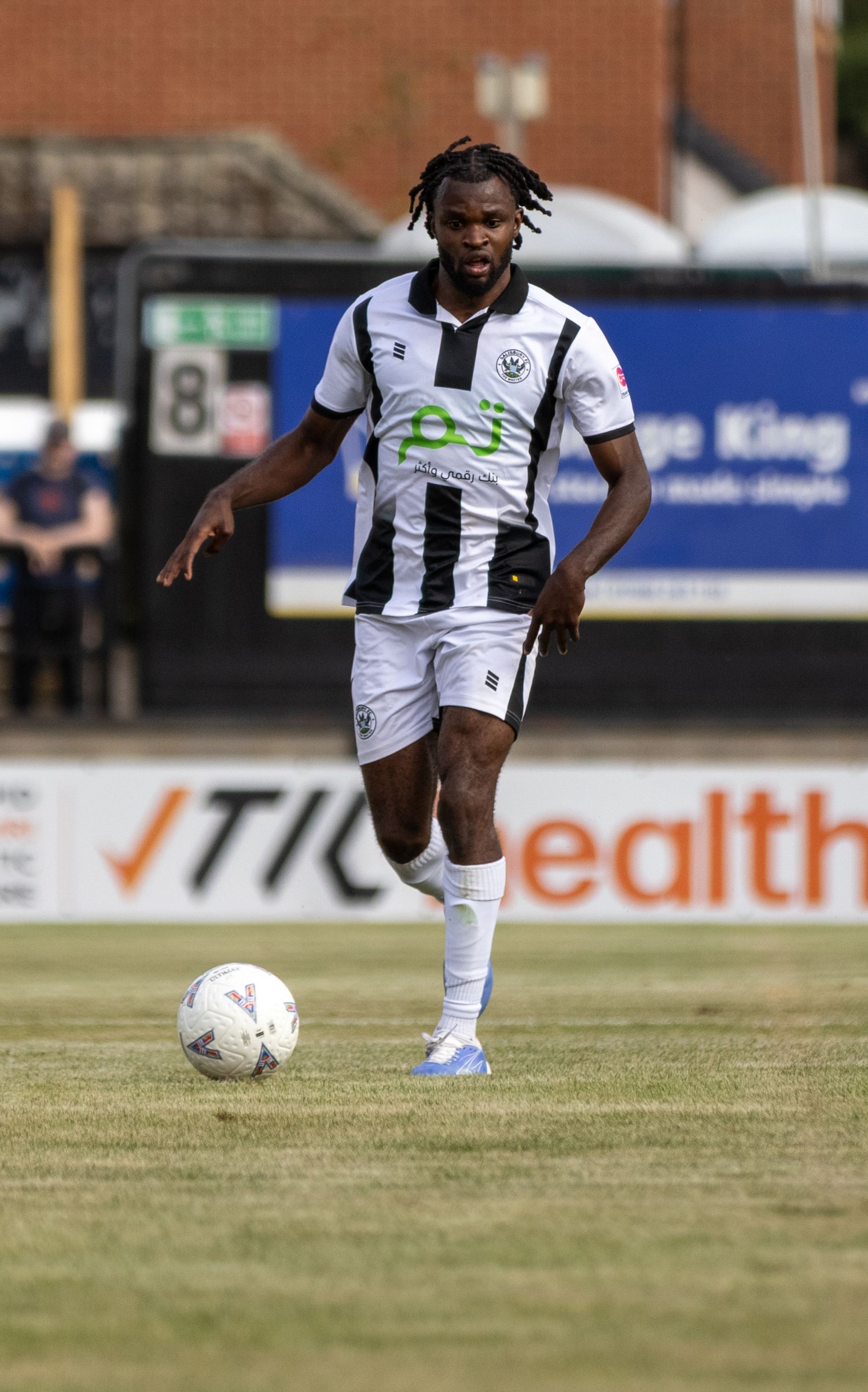 Salisbury FC defender in black and white kit controls the ball on a dry summer matchday.