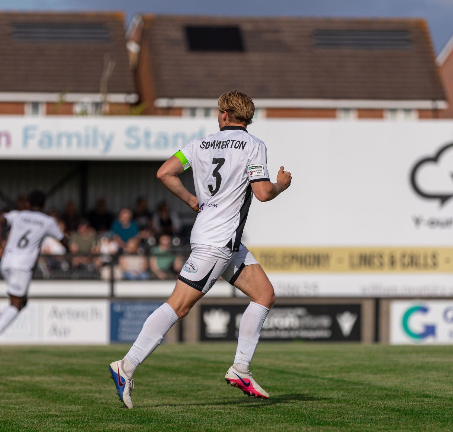 Soccer player number 3 Smarston in white kit jogging on a sunny matchday at a family stadium.