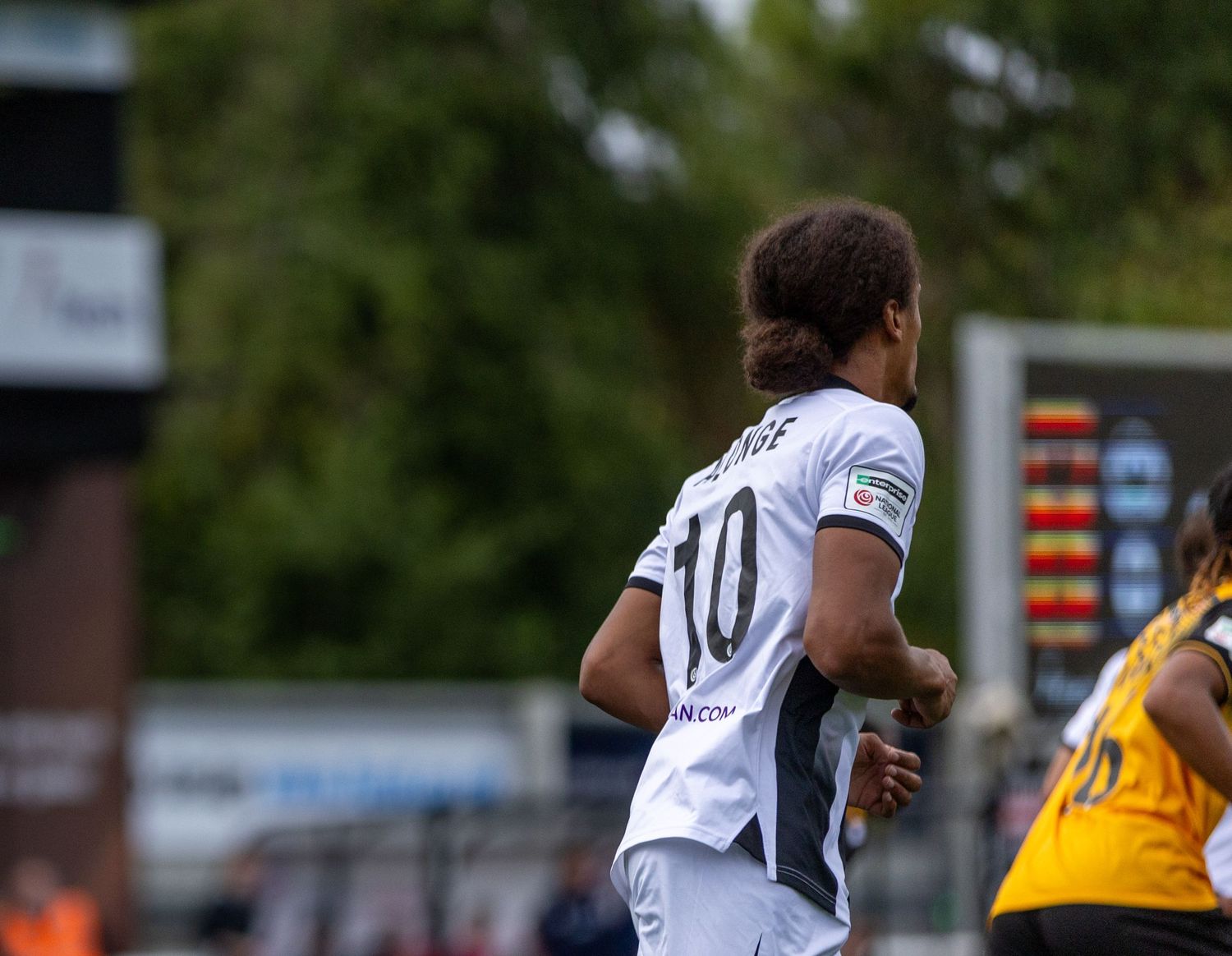 Soccer player wearing number 10 white jersey runs on field during a competitive match.