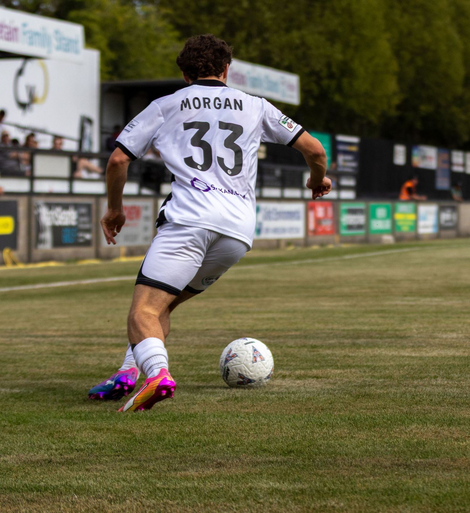 Football player Morgan wearing number 33 white kit prepares to strike the ball during an outdoor match.