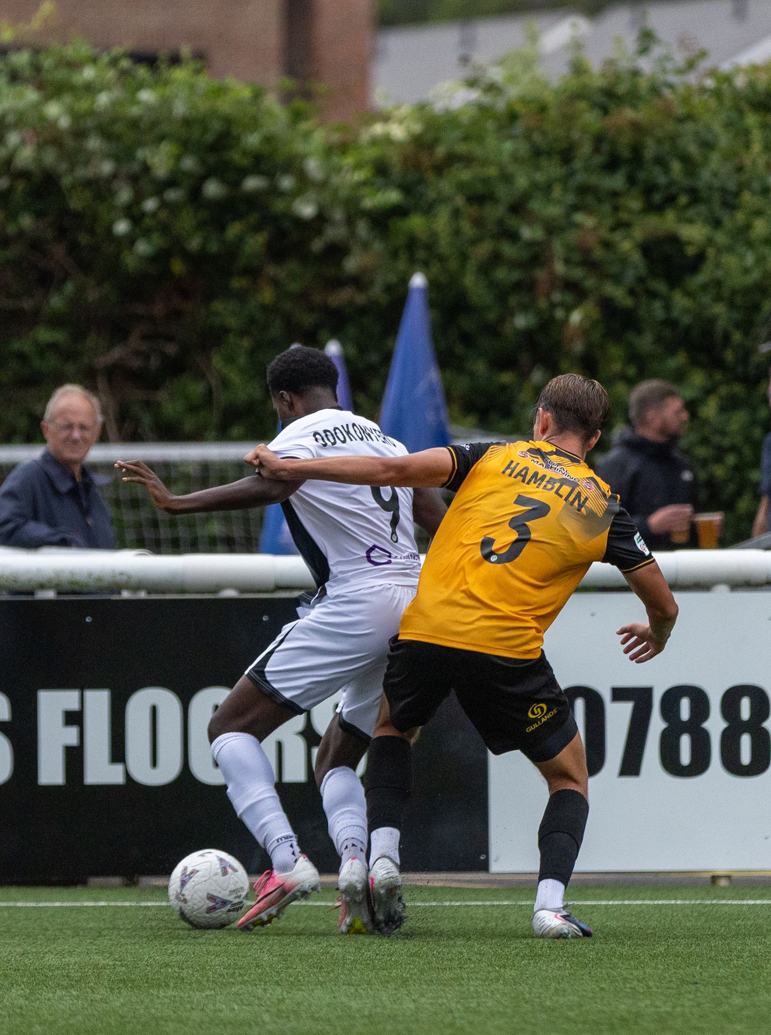 Two soccer players compete for the ball during a match, with player number 3 Hansen defending against an opponent in white.